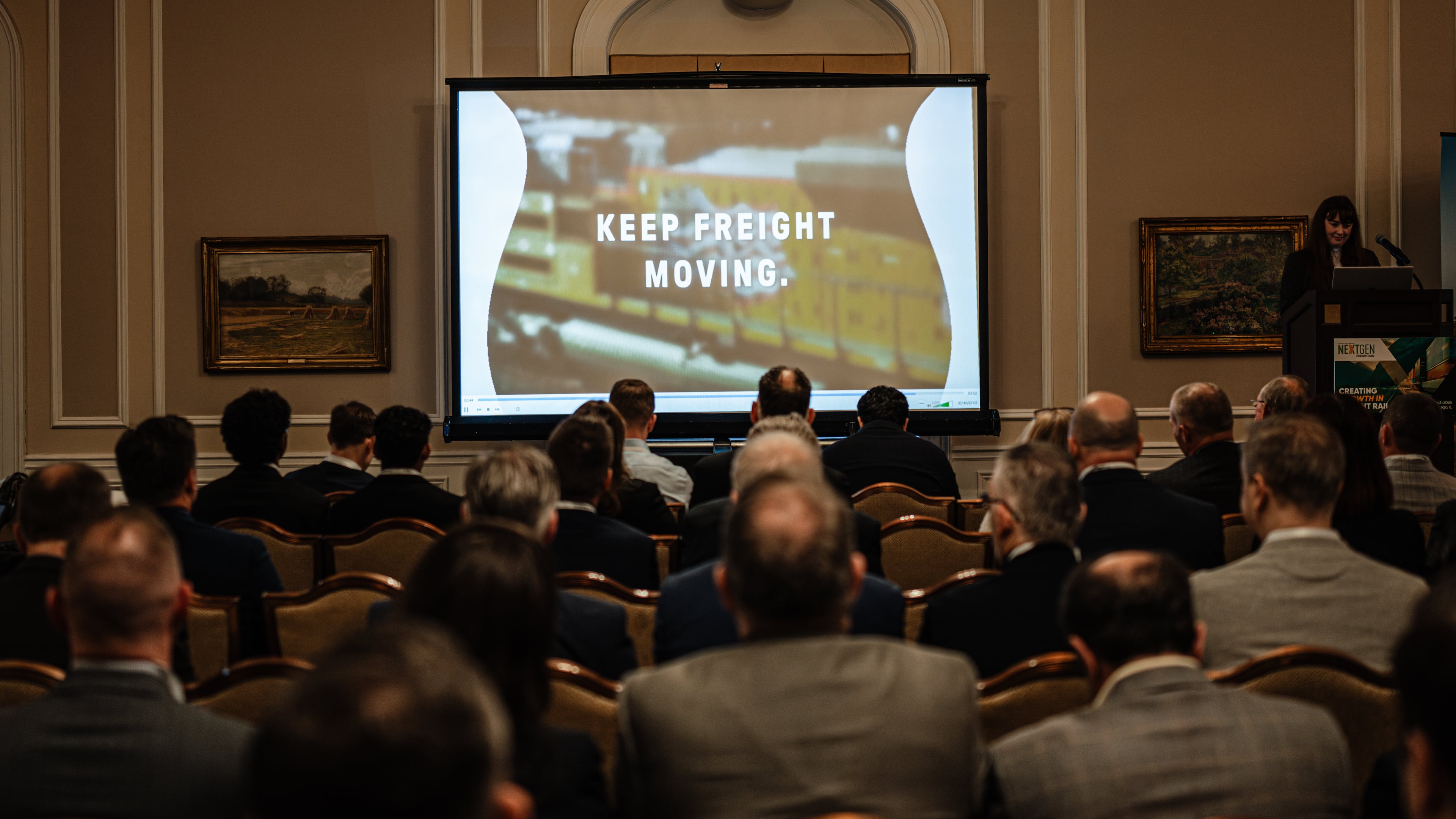 People watch an introductory short film about the proposed merger between Union Pacific and Norfolk Southern during the Railway Age’s Next-Gen Freight Rail conference on Tuesday, March 10, 2026, in Chicago. The merger could be leveraged by state and local leaders to kick-start the replacement of outmoded urban infrastructure, guest columnist Jeff Rader writes. (Jamie Kelter Davis for the AJC)