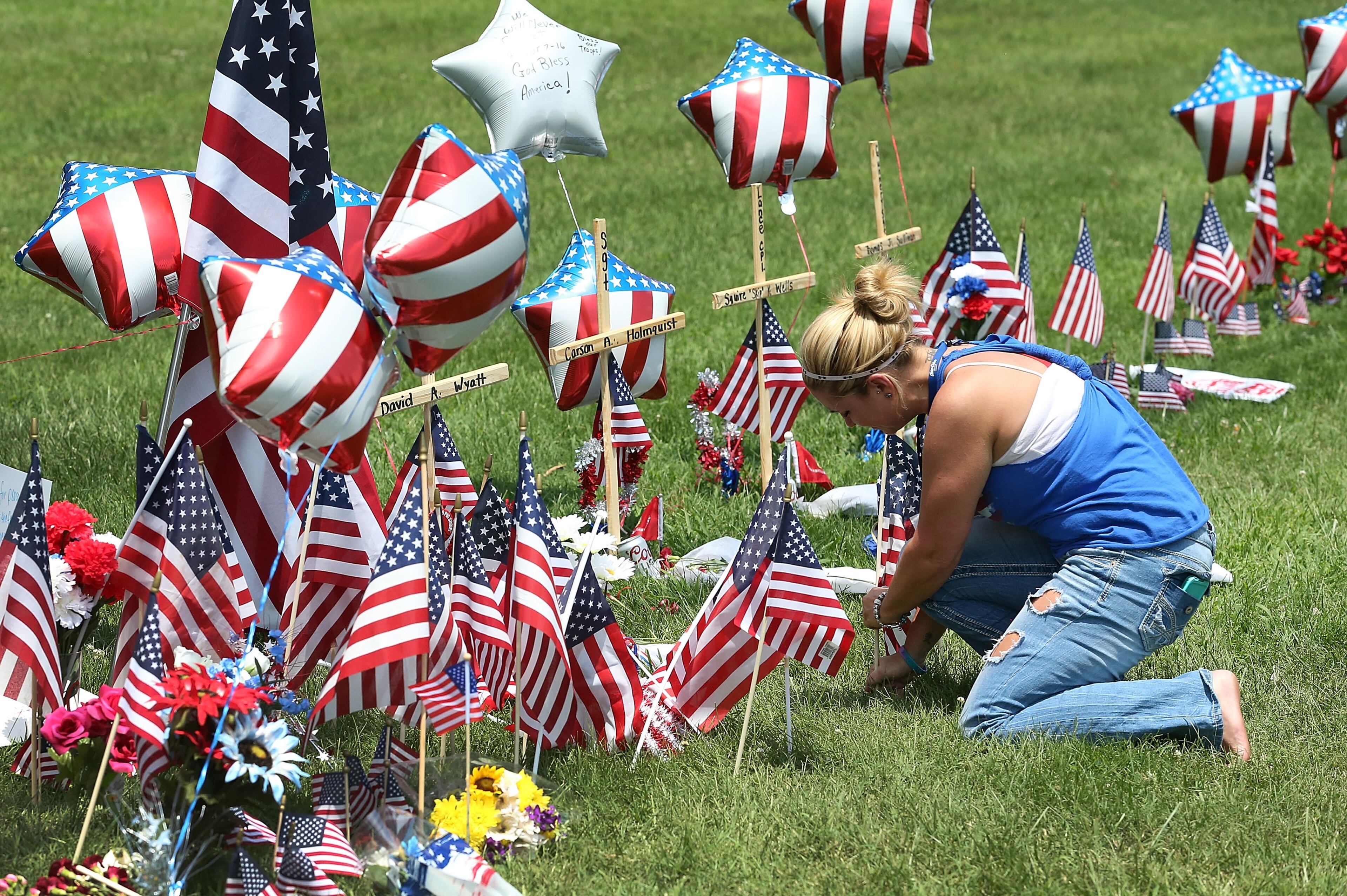 CHATTANOOGA, TN - JULY 18: Sophia Ensley places an American flag in a memorial setup in front of the Navy Operational Support Center and Marine Corps Reserve Center where four United States Marines and a Navy sailor were killed on July 18, 2015 in Chattanooga, Tennessee. According to reports, Mohammod Youssuf Abdulazeez, 24, opened fire on the military recruiting station at the strip mall on July 16th and then drove more than seven miles away to an operational support center operated by the U.S. Navy and killed four United States Marines and a Navy sailor. The gunman was likely killed in a exchange of gunfire with the police. (Photo by Joe Raedle/Getty Images)