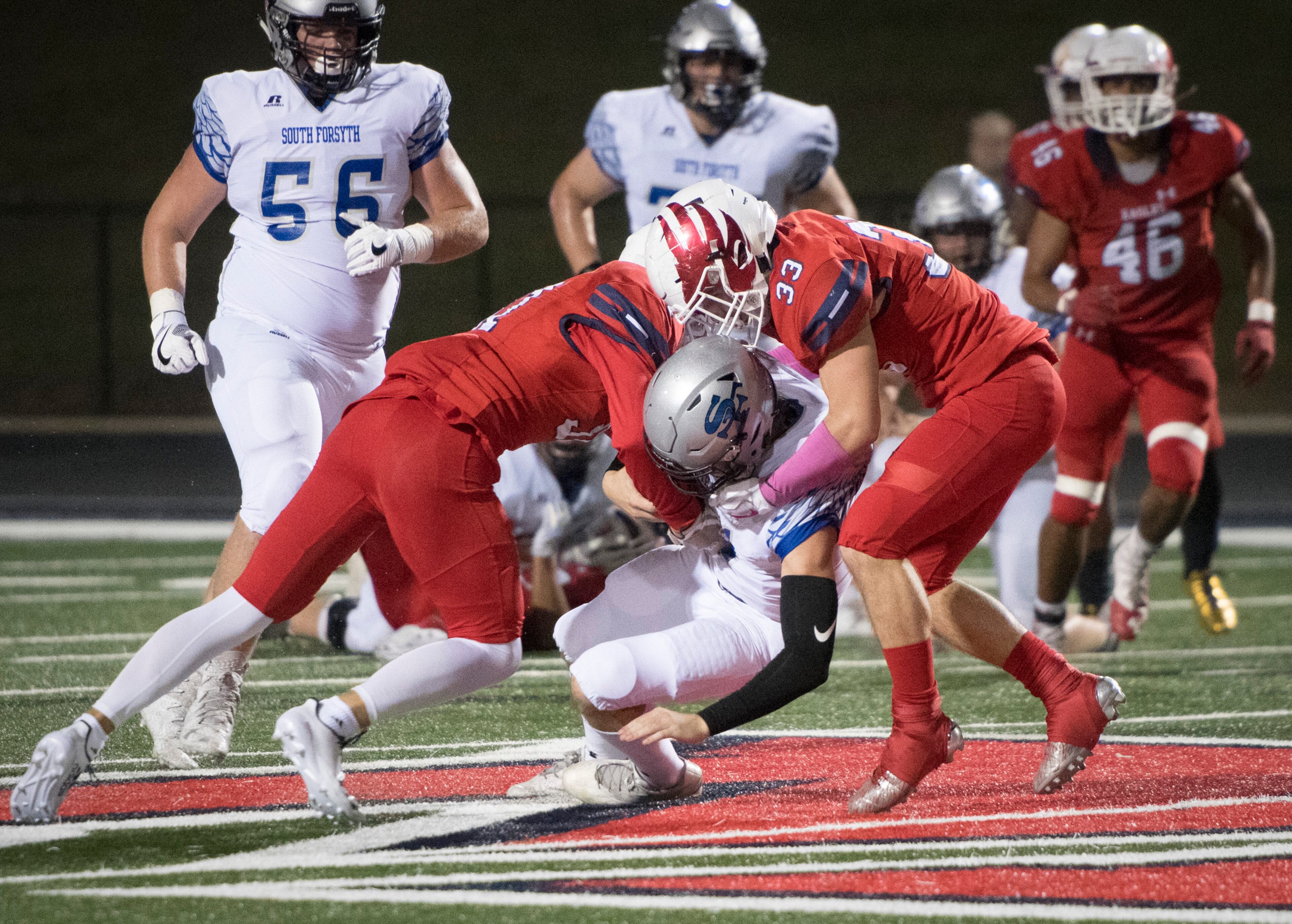 South Forsyth QB Cal Morris is tackled by Milton FS Jack Rhodes, left, and LB Price Townes, right, during a high school football game, Friday, Oct. 13, 2017, in Milton. (John Amis)