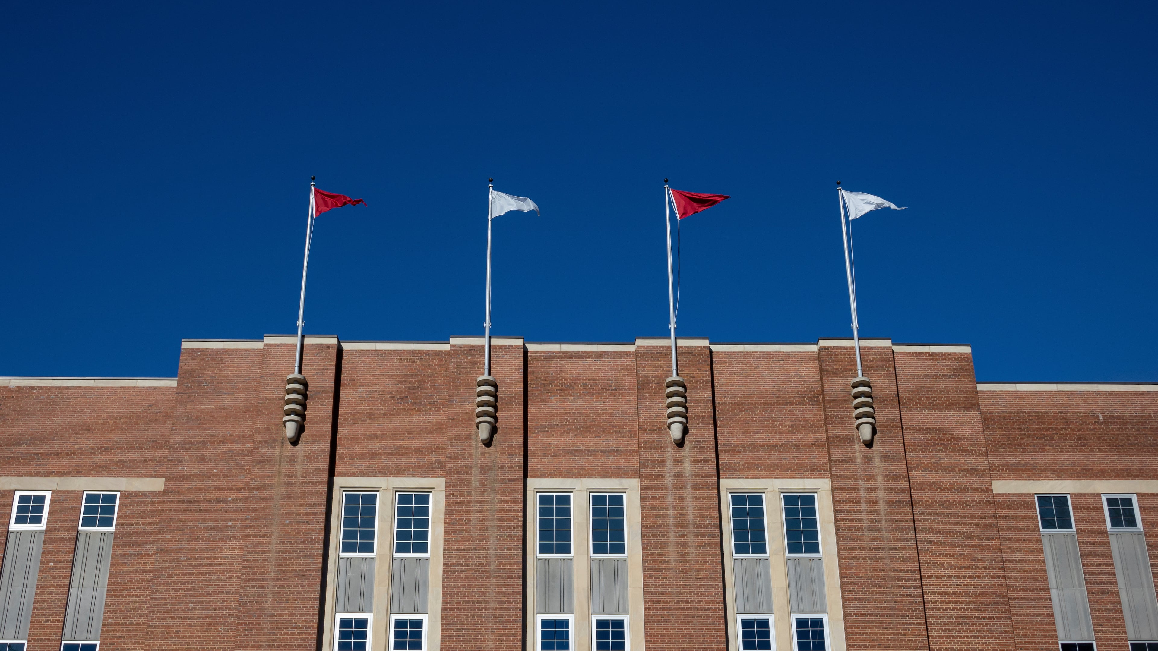 FILE - Flags fly above at the Reynolds Coliseum on the campuse of North Carolina State University, Feb. 19, 2022, in Raleigh, N.C. (AP Photo/Kara Durrette, File)