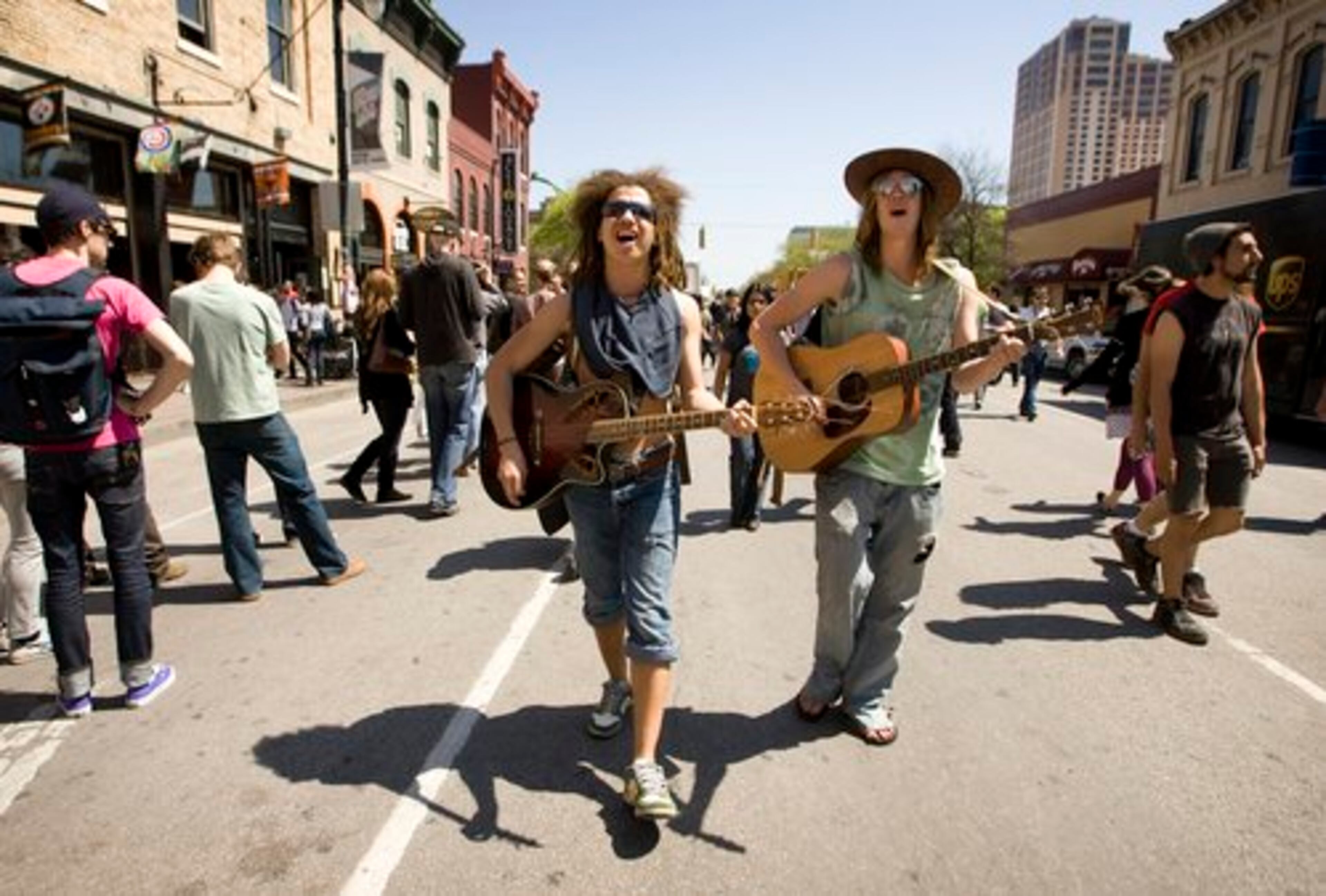 Dustin O'Harver, left, and Timothy Kallevig, of the Minneapolis band "Dustin Thomas" sings as they walk along 6th Street during SXSW.