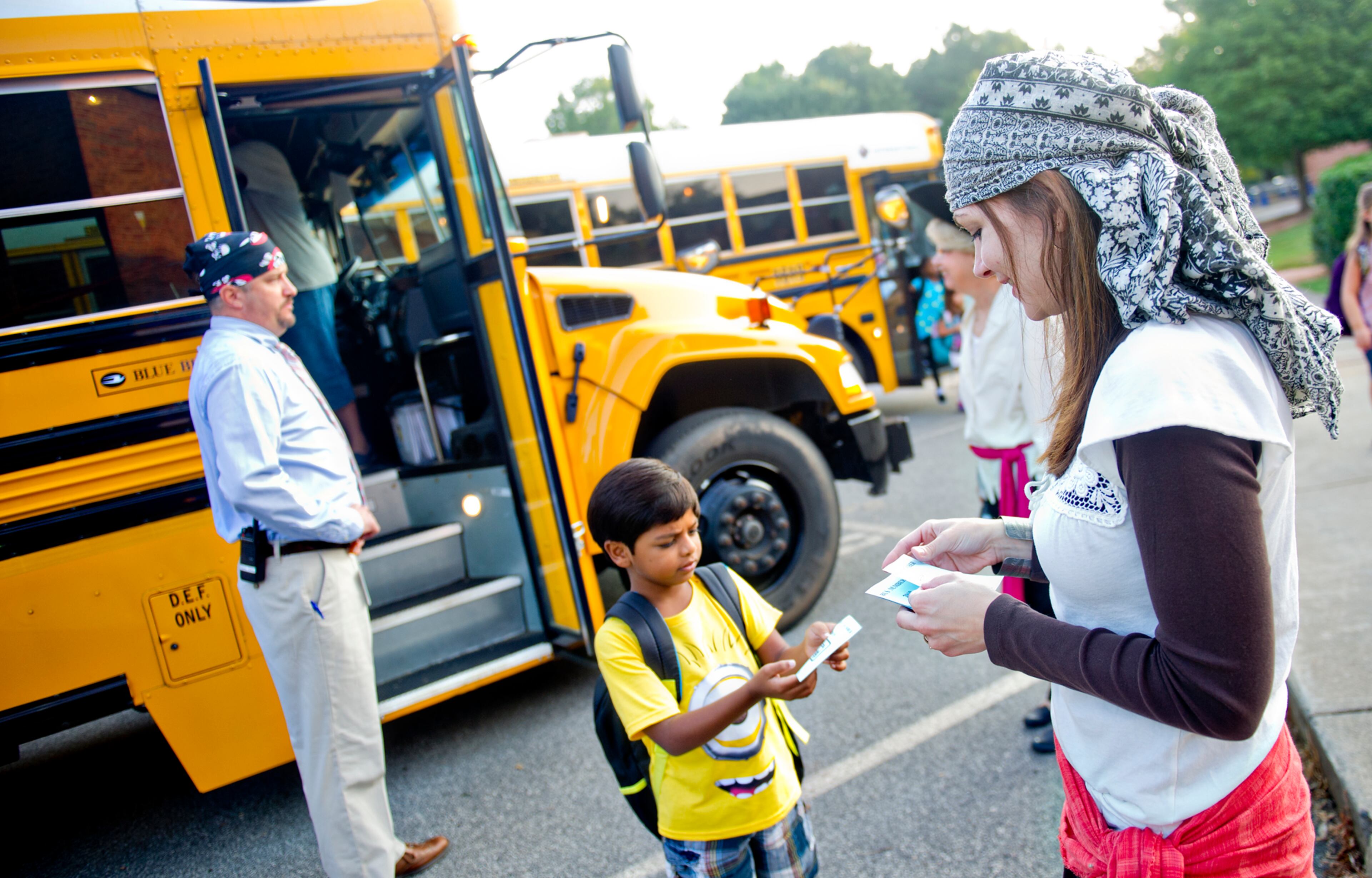 Nora Sanders (right) hands Viraj Sheel a notecard as he steps off the bus at Davis Elementary School in Marietta on Monday, August 4, 2014. Teachers and administrators at the school dressed as pirates for the first day of classes. Students in Cobb County and Atlanta public schools headed back to class on Monday for the new school year. JONATHAN PHILLIPS / SPECIAL