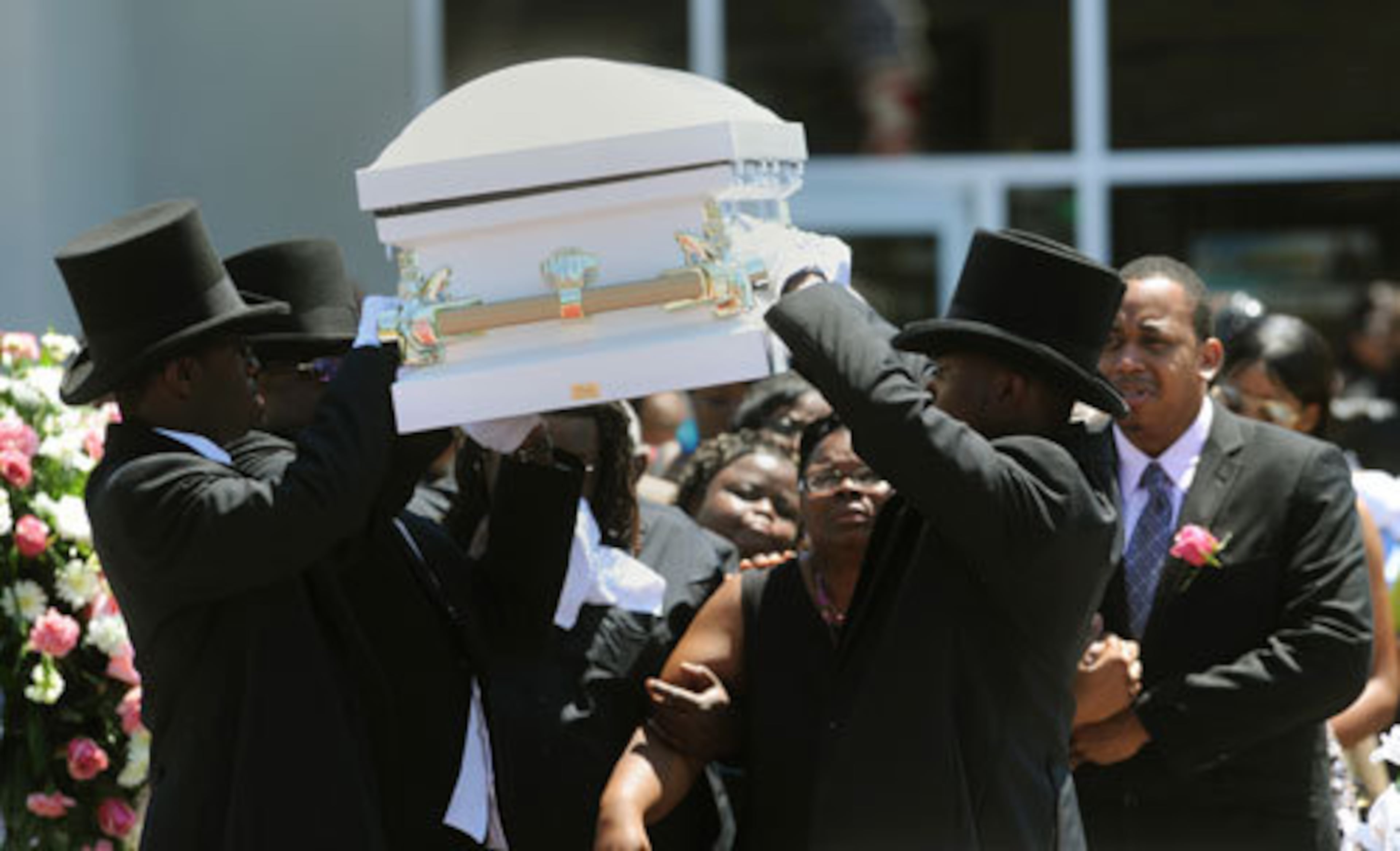 Pallbearers from the Willie A Watkins Funeral Home lift the casket containing the body of toddler Jazmin Green on their shoulders as her mother, April McAlister, and father, Charles Green, watch.