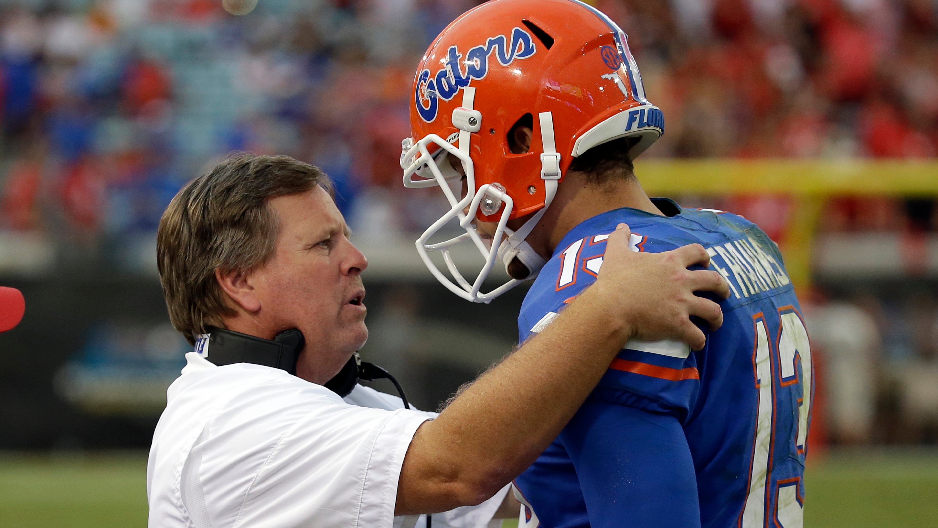 Florida head coach Jim McElwain talks with quarterback Feleipe Franks (13) on the sideline in the second half of an NCAA college football game against Georgia, Saturday, Oct. 28, 2017, in Jacksonville, Fla. Georgia won 42-7. (AP Photo/John Raoux)