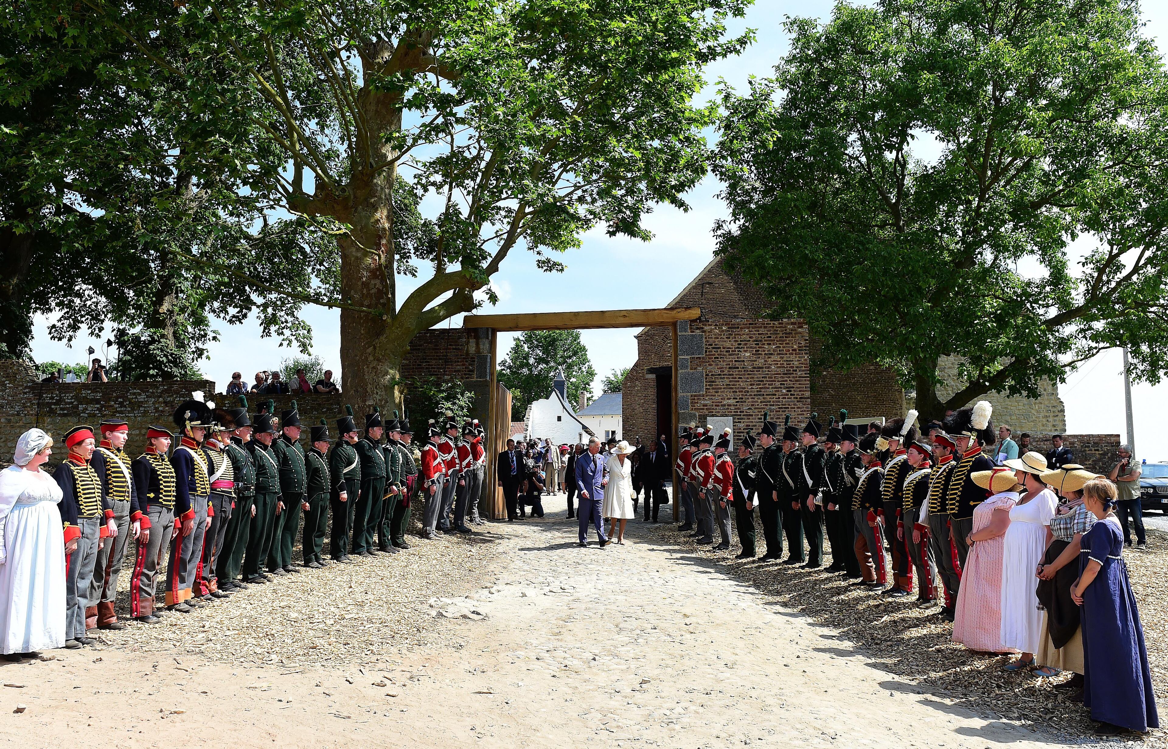 Charles, Prince of Wales, center left, and Camilla, Duchess of Cornwall, center right, arrive for the ceremonial opening of Hougoumont Farm in Braine-l'Alleud, near Waterloo, Belgium on Wednesday, June 17, 2015. The fully restored farm opens to the general public on June 18, 2015, which is the 200th anniversary of the Battle of Waterloo. (AP Photo/Emmanuel Dunand/Pool Photo via AP)