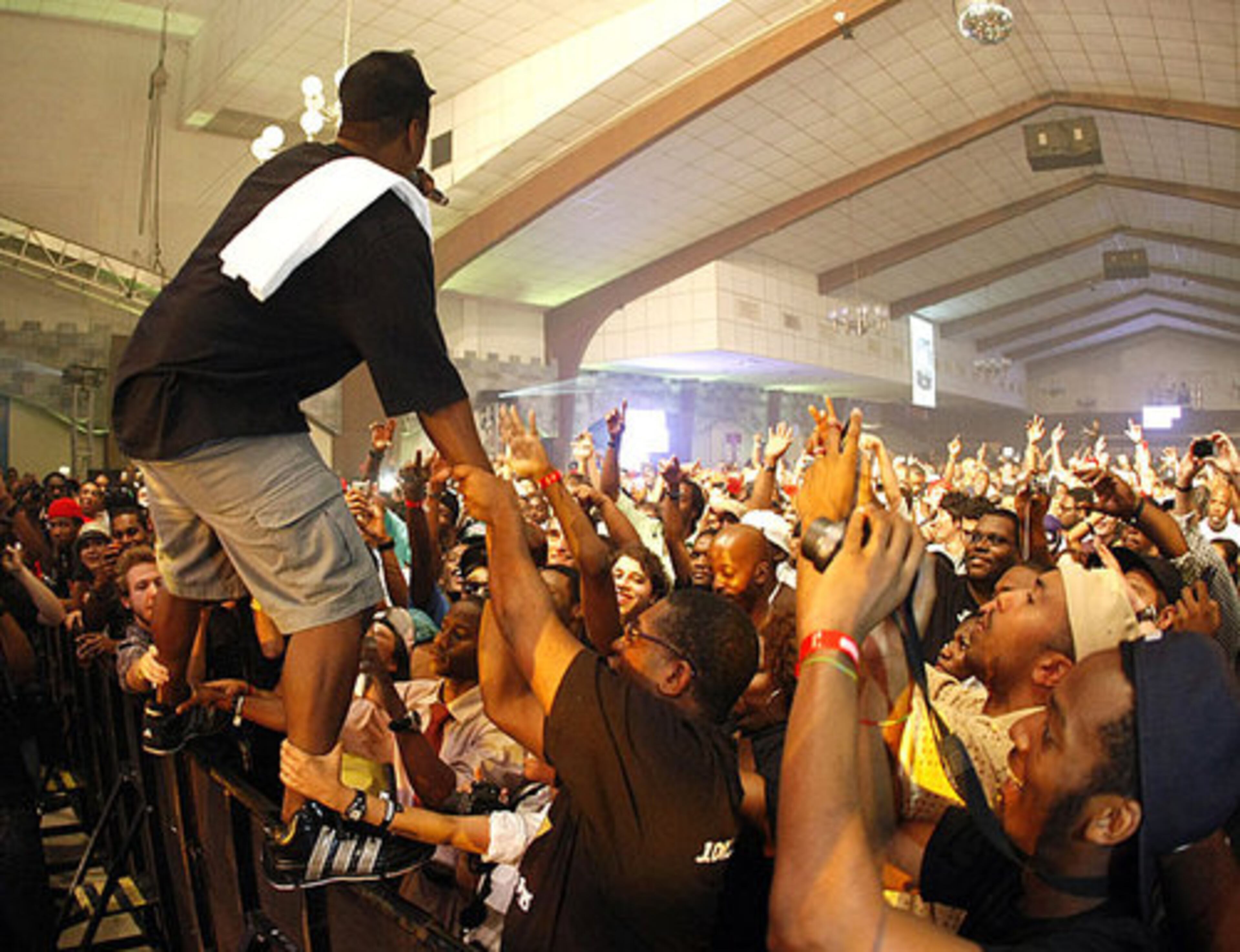 Jay Electronica, a rapper and producer known for his use of percussionist film soundtracks, climbs onto a stage barricade.
