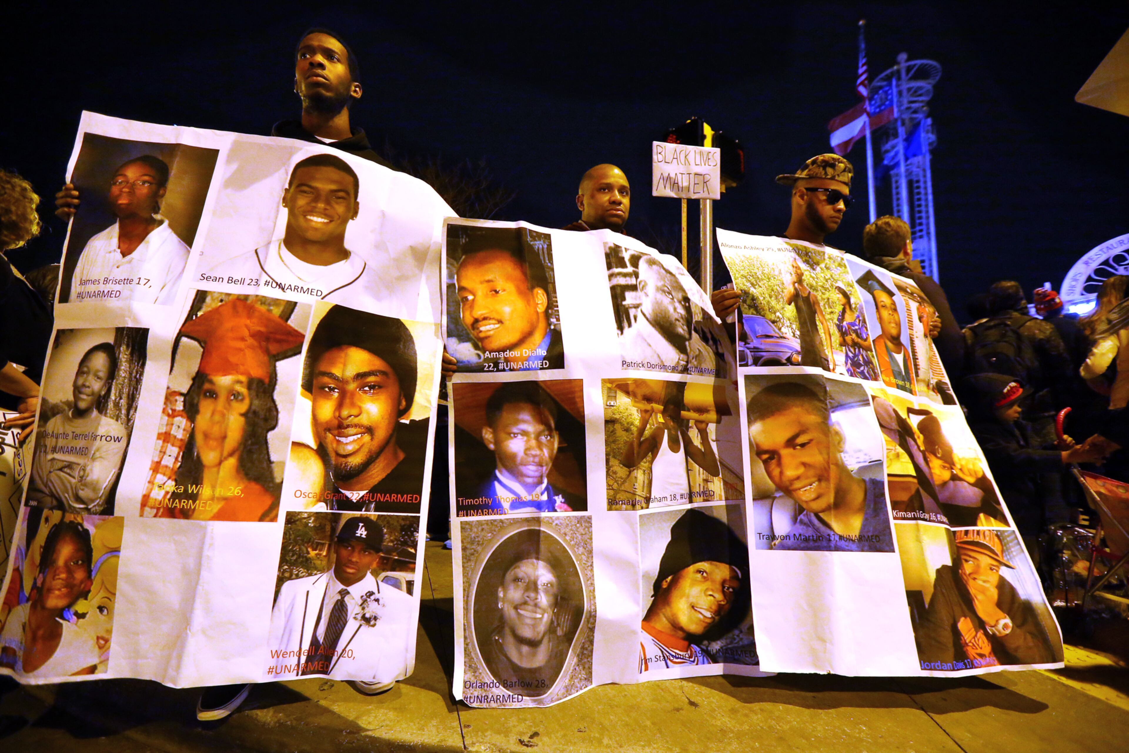 Bishop Nesby (from left), Anthony Hegler, and Manny Berry, all from Kennesaw State University, join in a protest at Undereground Atlanta in the wake of the grand jury decision not to indict officer Darren Wilson in the shooting death of Ferguson, MO., teen Michael Brown. The men are holding what they say are photographs of unarmed African Americans that have been shot and killed by law enforcement officers. CURTIS COMPTON / CCOMPTON@AJC.COM