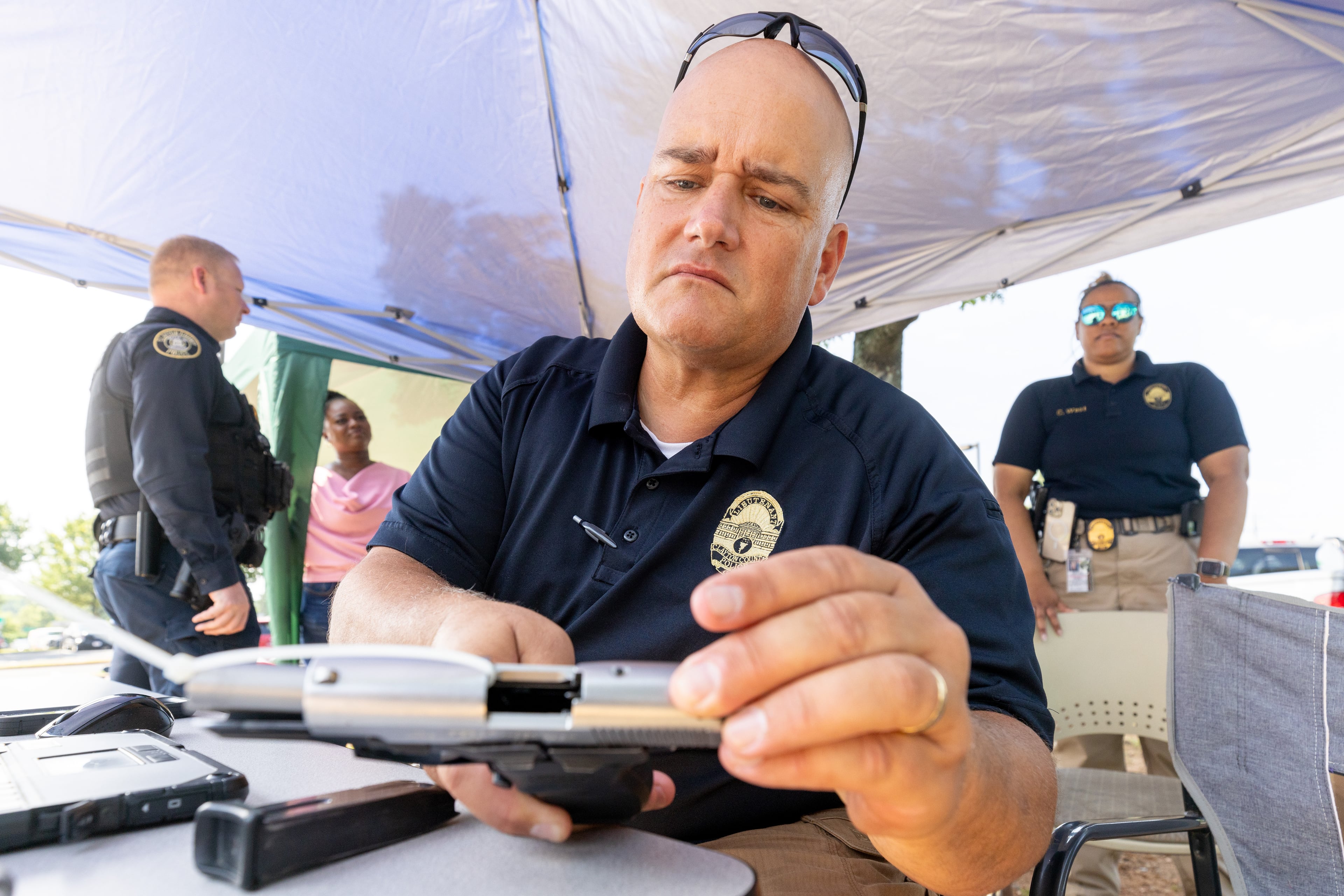 Clayton County police Lieutenant Taylor Davis holds a stolen handgun discovered during the Clayton County gun buyback program on Saturday, June 24, 2023. (Steve Schaefer/steve.schaefer@ajc.com)