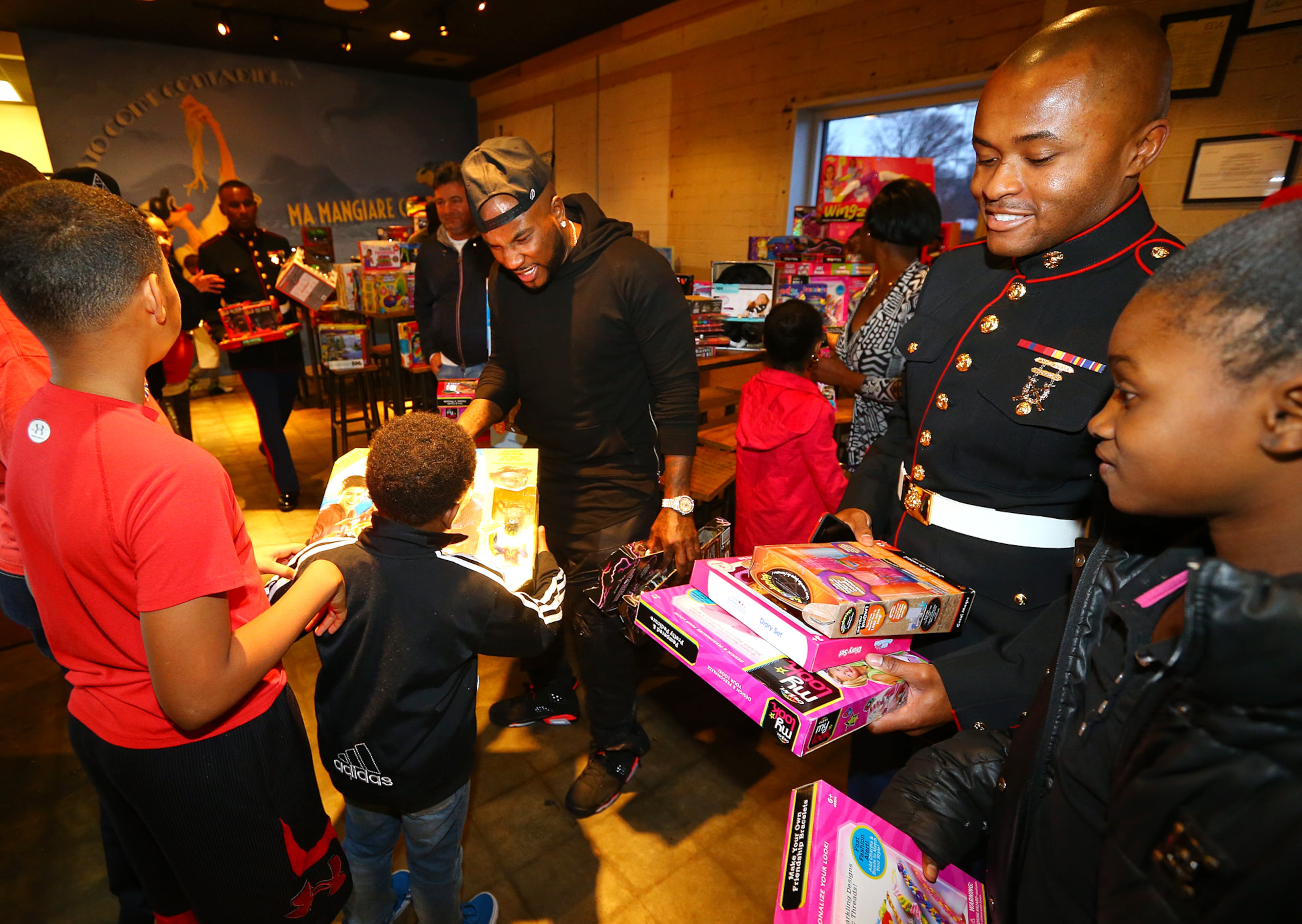 Jeezy, aka Jay Jenkins, with an assist from Marine Sgt. Rod Belcher, hands out toys to around 200 needy inner city kids from Macon, Hawkinsville, and Atlanta for Christmas on Monday, Dec. 22, 2014, in Atlanta. The children were treated to a private screening of the movie Annie, followed by food and toys given out by "Santa Jeezy" at Gio's. Curtis Compton / ccompton@ajc.com