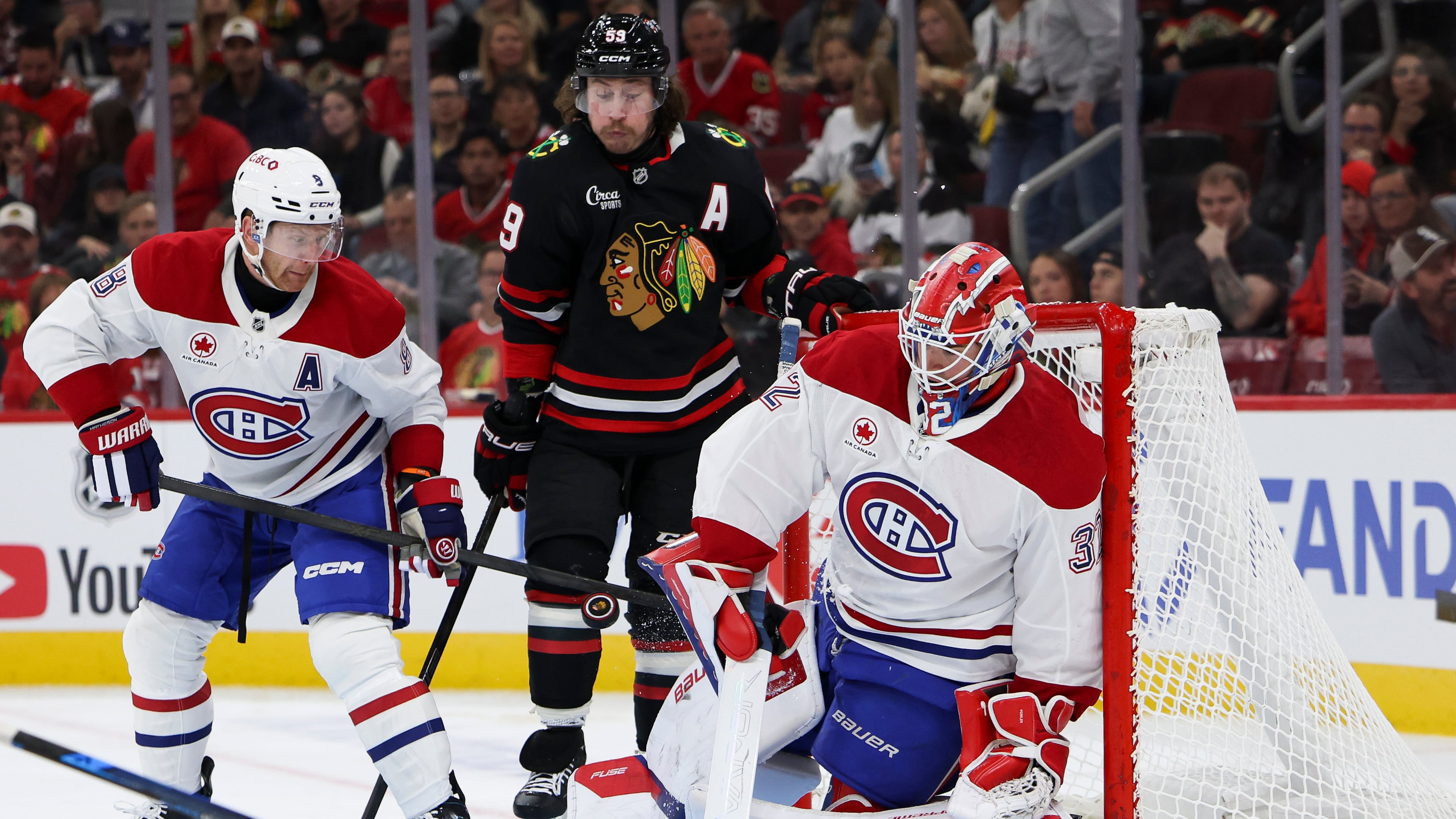 Montreal Canadiens goaltender Jacob Fowler, right, makes a save as defenseman Mike Matheson, left, and Chicago Blackhawks left wing Tyler Bertuzzi, center, watch during the second period of an NHL hockey game, Friday, Oct. 23, 2026, in Chicago. (AP Photo/Jessie Alcheh)