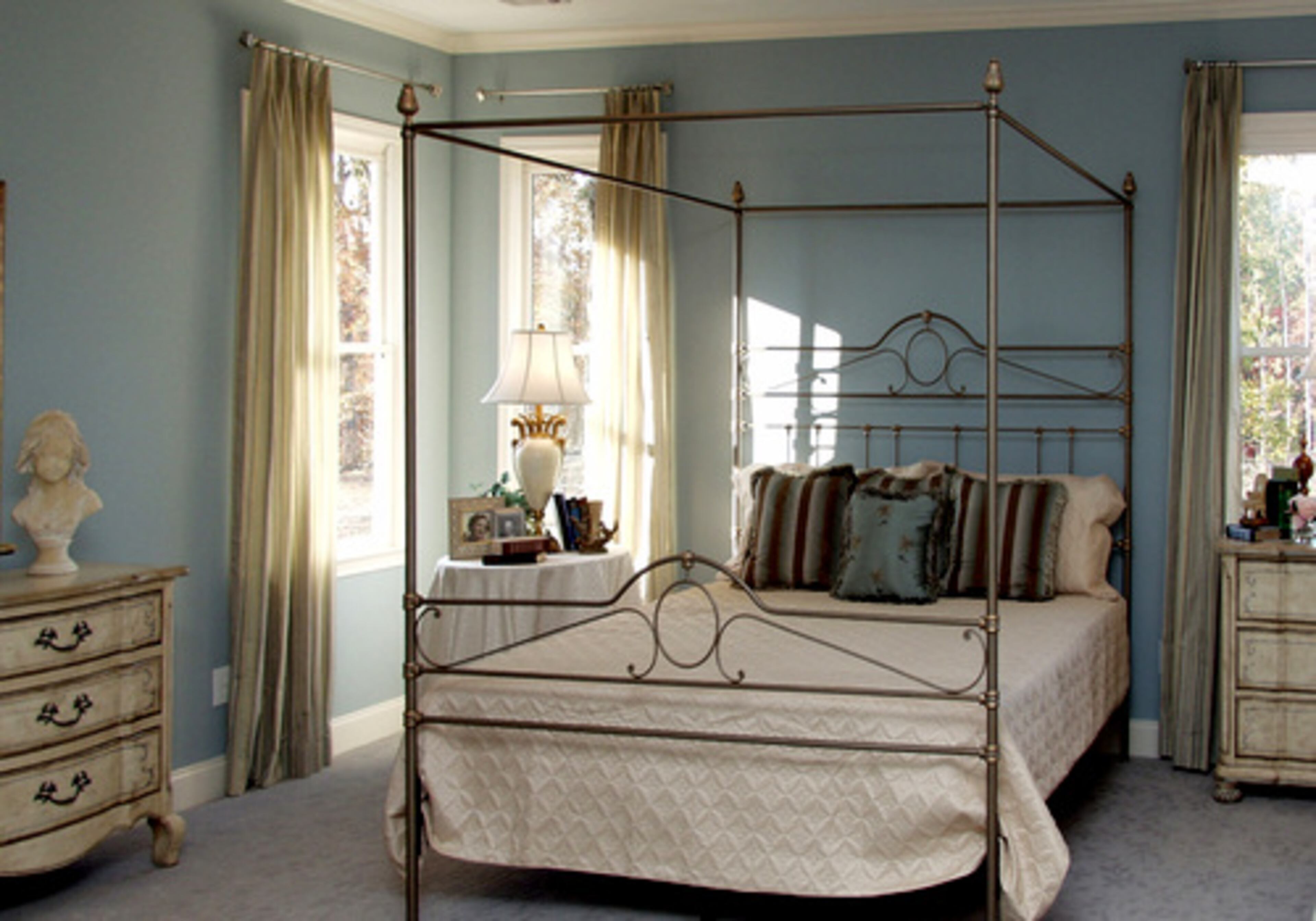 MASTER RETREAT: Calming French blue plays a major role for the wall color, accent pillows and window treatments. The white matelasse bedcover gives a crisp look. The chests are modified French Provincial, painted pale cream with detailing in French blue.