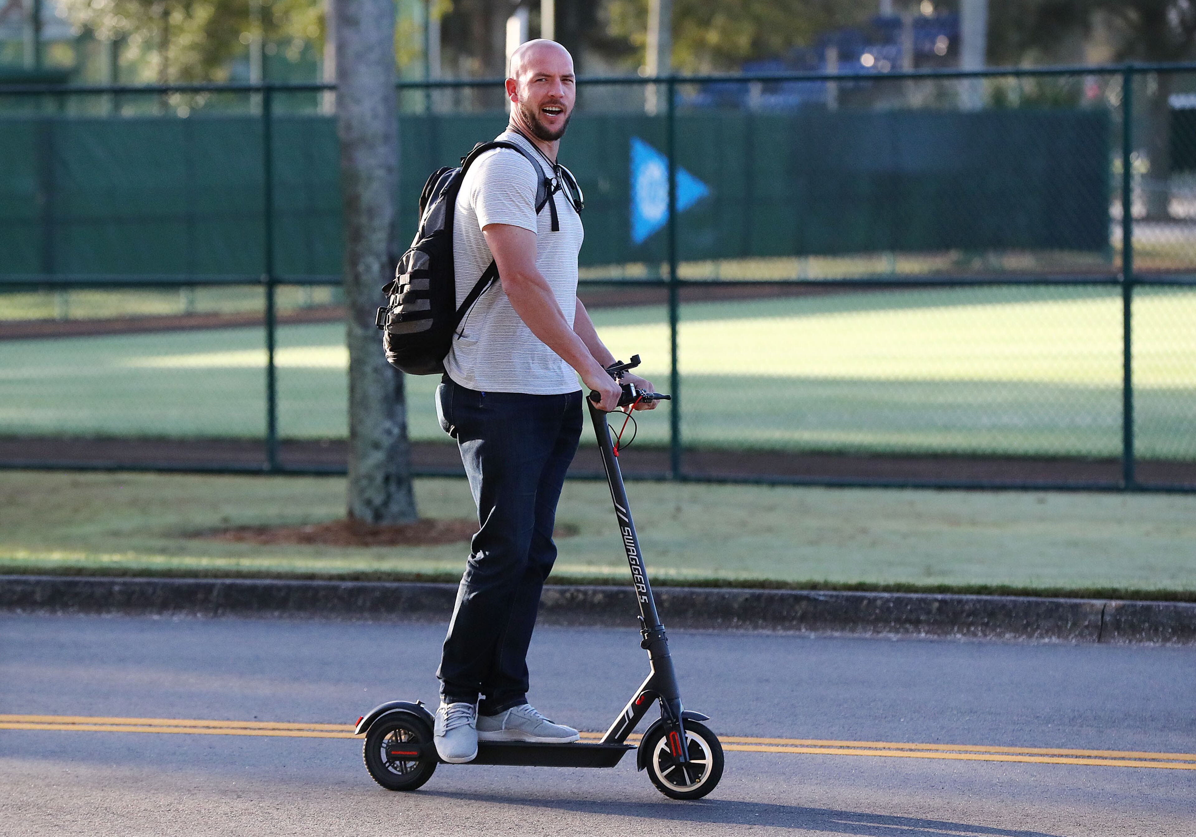 It's time for baseball: Tyler Flowers arrives on a scooter as pitchers and catchers reported to Braves spring training Friday in Lake Buena Vista, Fla. (Curtis Compton/ccompton@ajc.com)