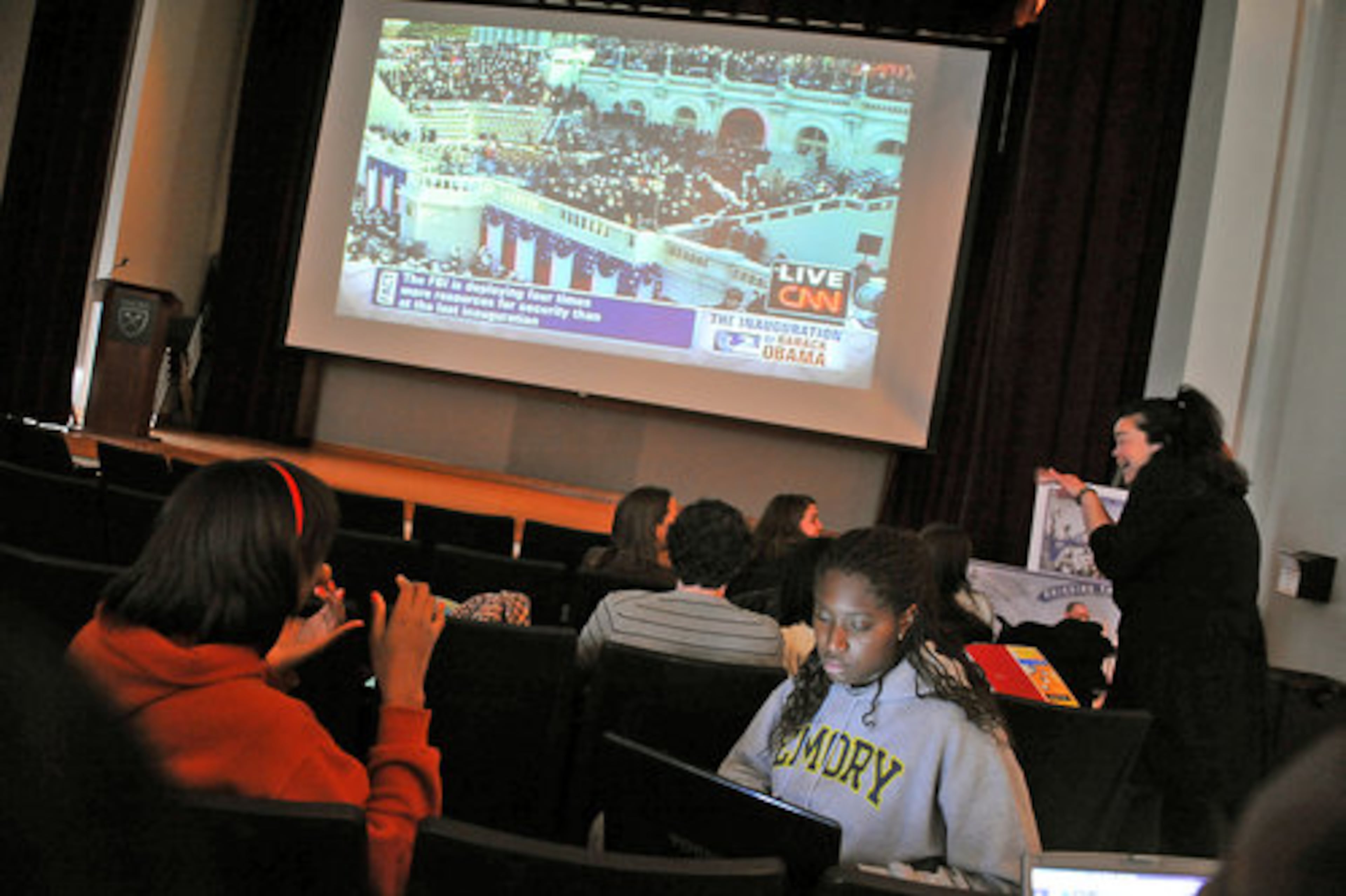 Crystal Azu (in gray), a junior at Emory University, works on homework while waiting for the presidential inauguration to begin in Harland Cinema on the university campus. Azu is from the Washington, D.C., area.