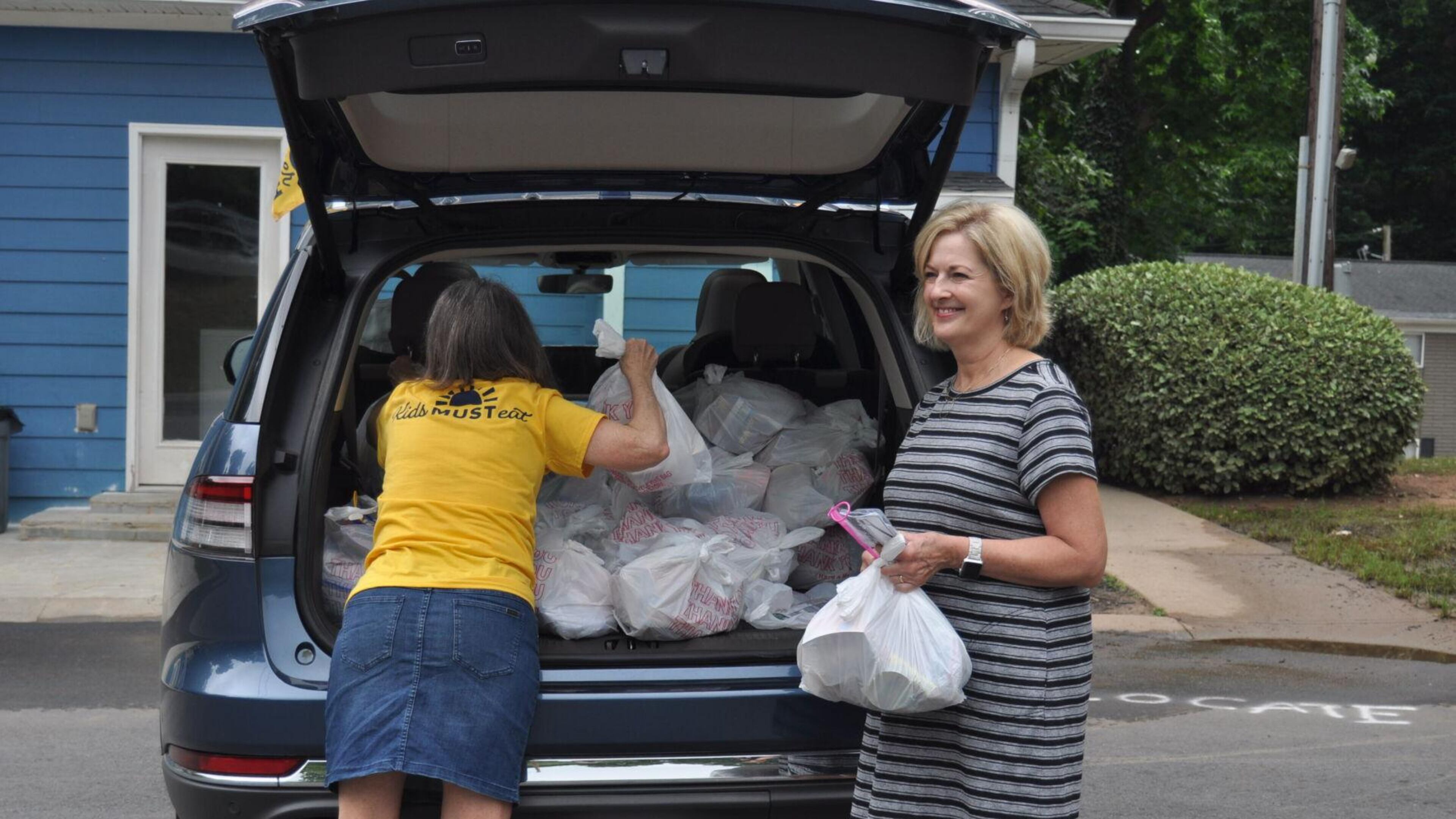 Two volunteers, Eleanor Knox (left) and Nancy Law (right) from First Presbyterian Church in Marietta hand out meals to children for MUST Summer Lunch, a program that works to ease food insecurity for children while they are out of school for the summer.