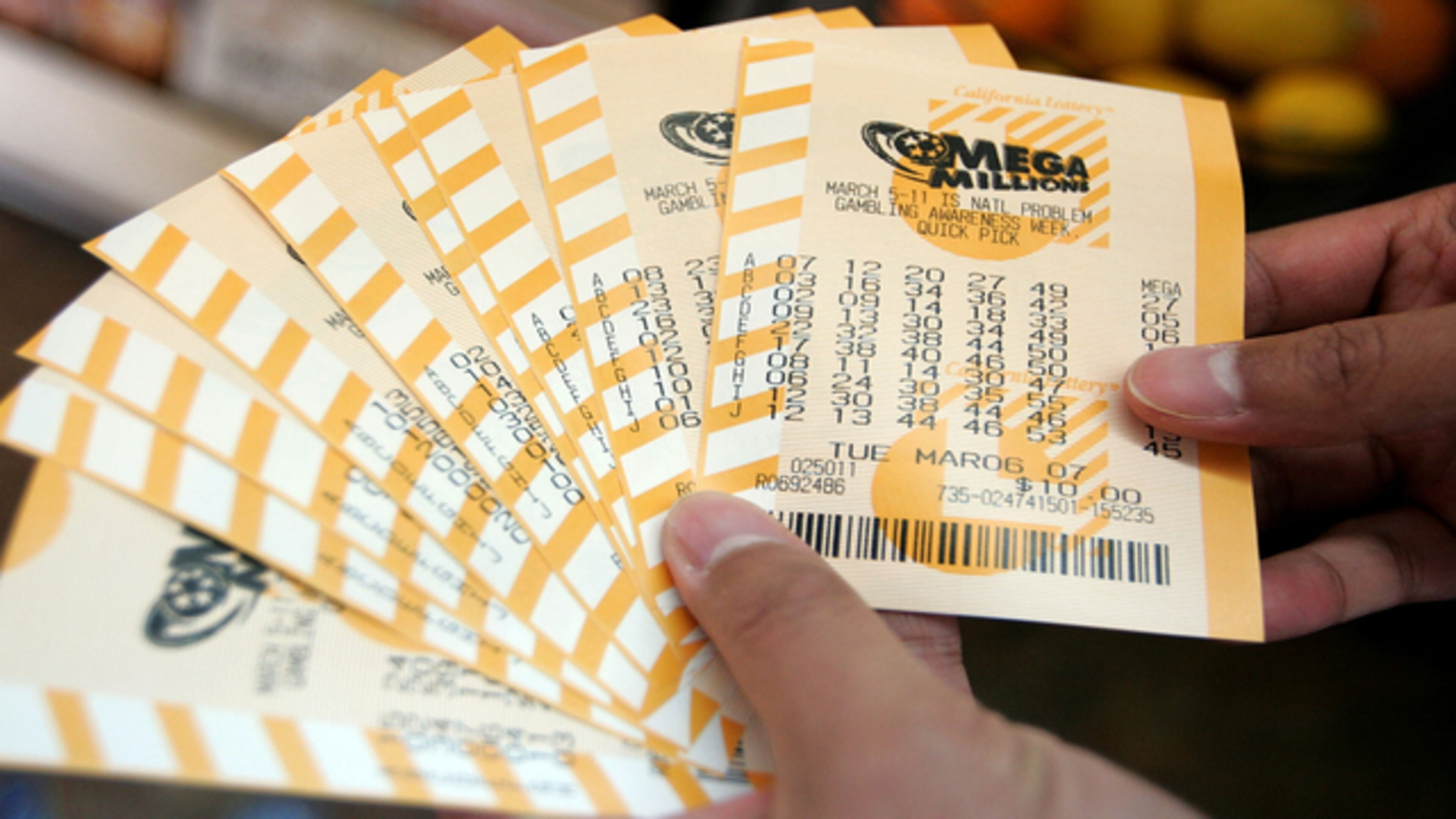 <p>Man holds a bundle of Mega Millions lottery tickets </p>