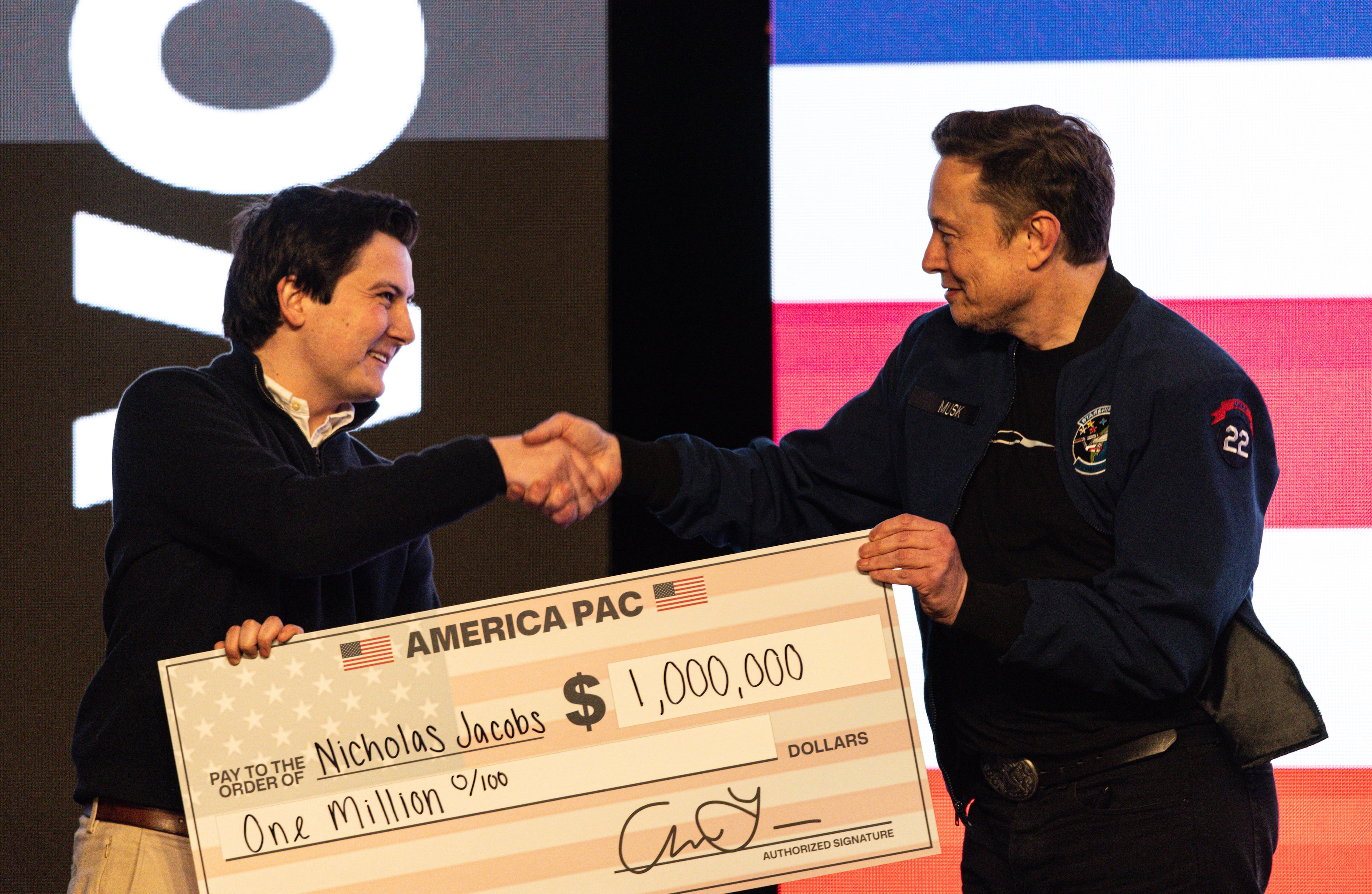 Tech titan Elon Musk (right) hands over a $1 million check during a town hall in Green Bay, Wisconsin, in March 2025. (Jeffrey Phelps/AP)