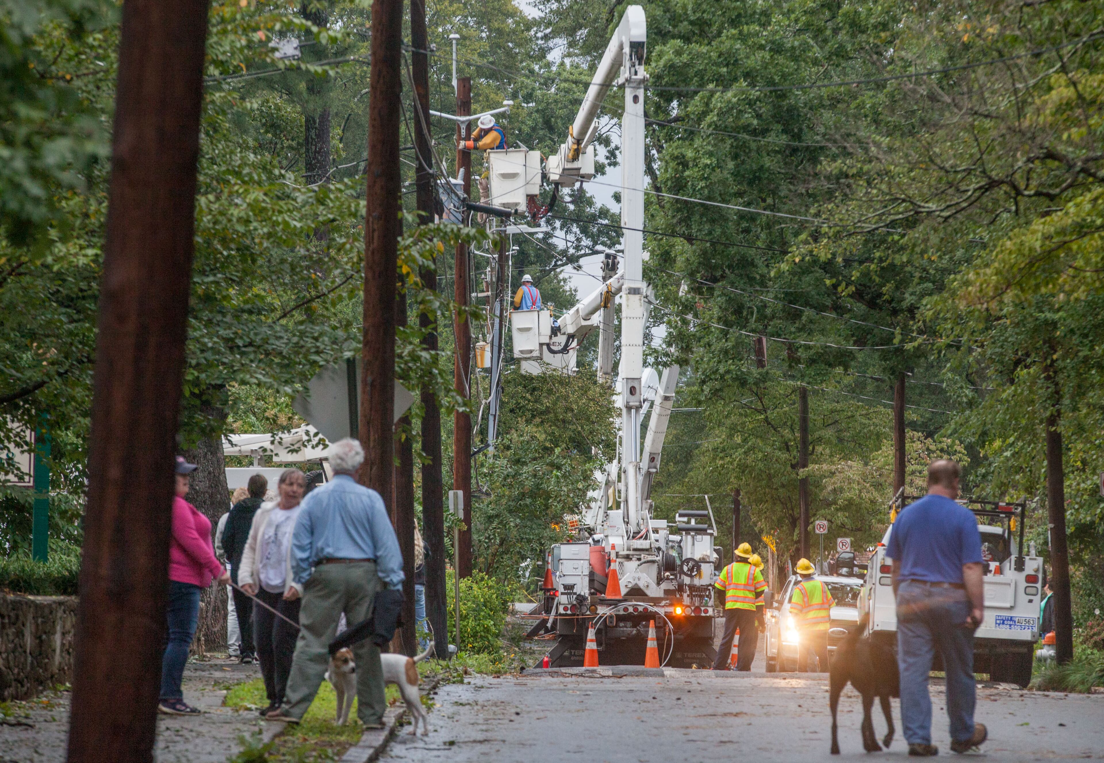 Residents walk on Adair Street as workers from Utility Lines Construction Services, a Delaware based company, work to restore power, Tuesday, Sept. 12, 2017, in Decatur, Ga. BRANDEN CAMP/SPECIAL