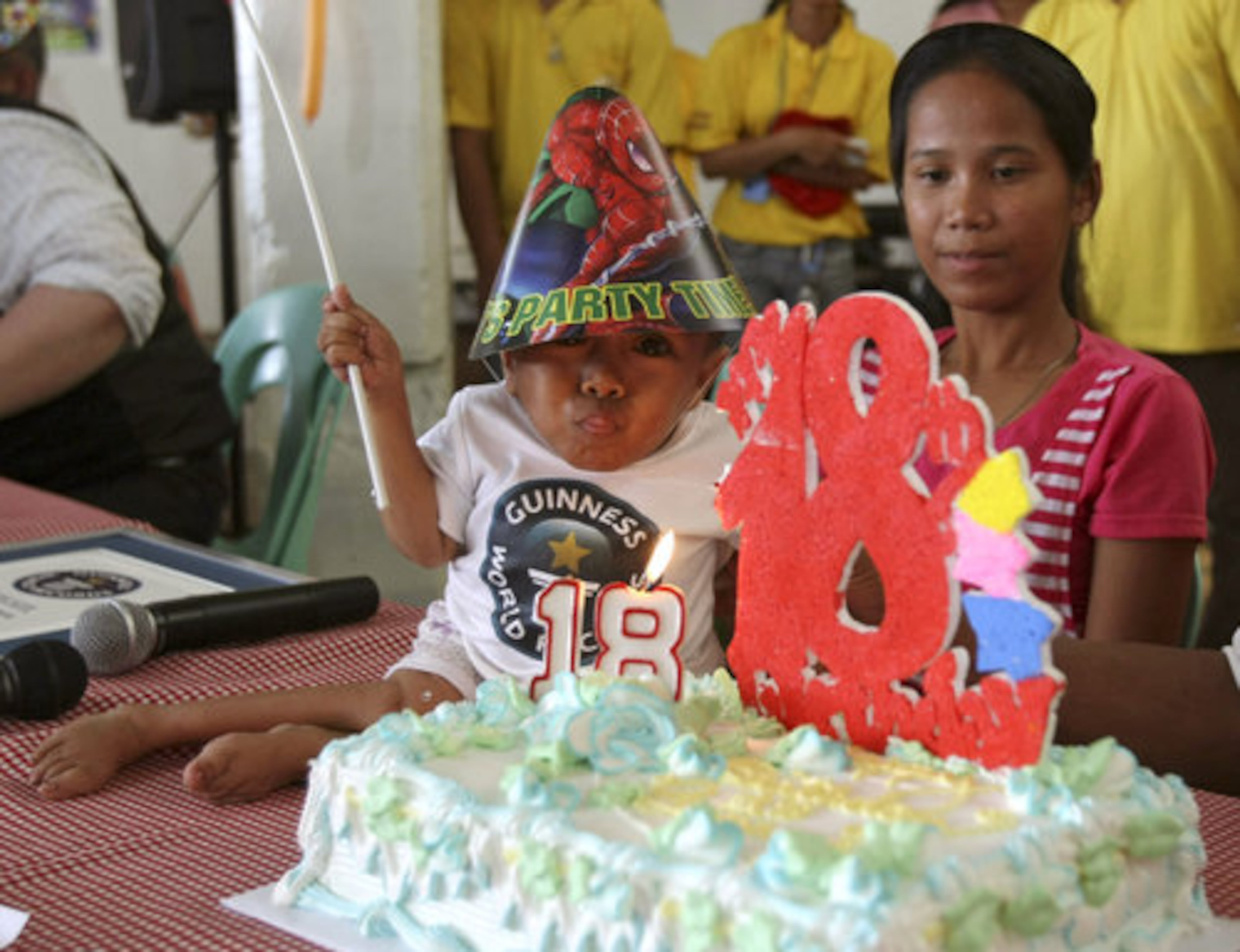 Junrey Balawing, center, blows a candle as he celebrates his 18th birthday after being declared 'the world's shortest living man' by the Guinness World Records adjudicator Craig Glenday.