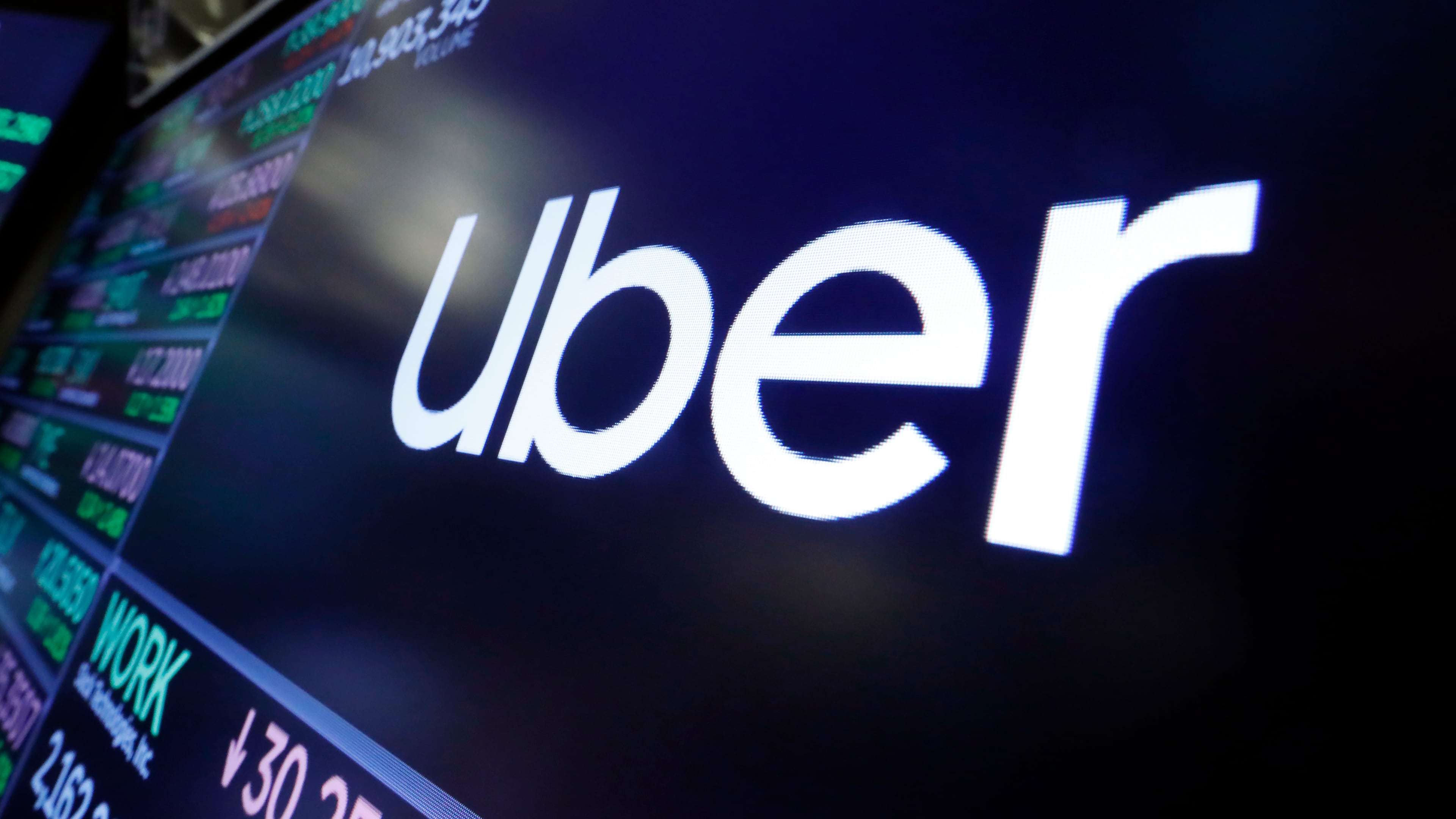 FILE - The Uber logo appears above a trading post on the floor of the New York Stock Exchange, Aug. 16, 2019. (AP Photo/Richard Drew, File)