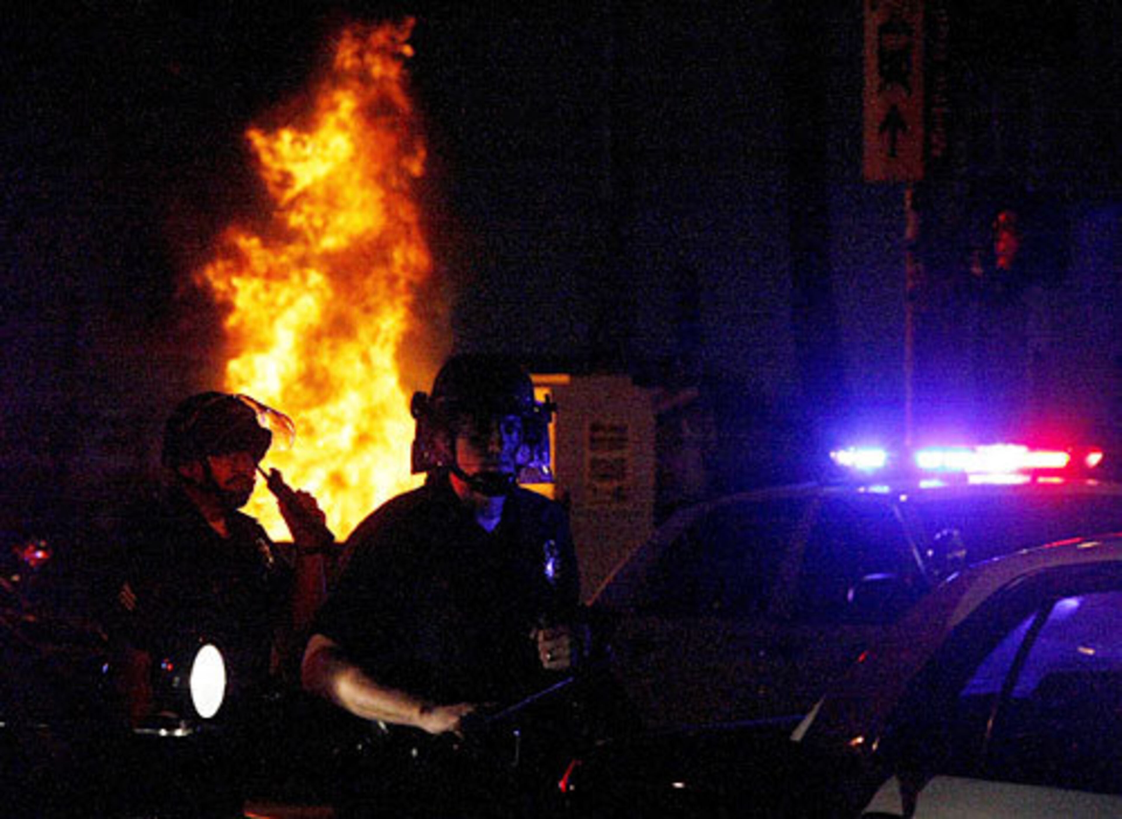 Los Angeles police officers are illuminated by a fire started by Lakers fans.