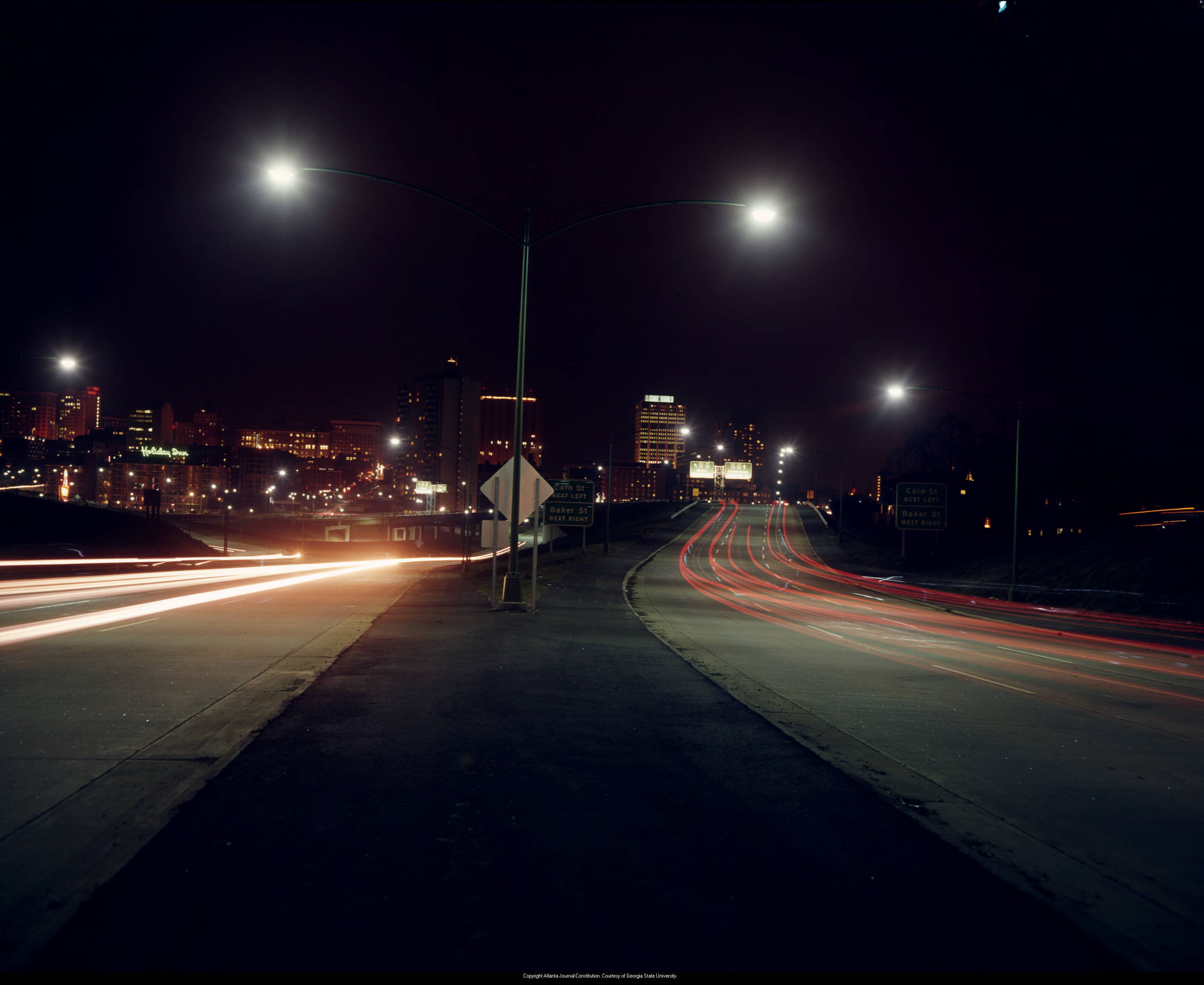 Time-lapse night photo looking northwest on the Downtown Connector at the exit for Cain Street (now John Wesley Dobbs Avenue) and Baker Street, October 1964.