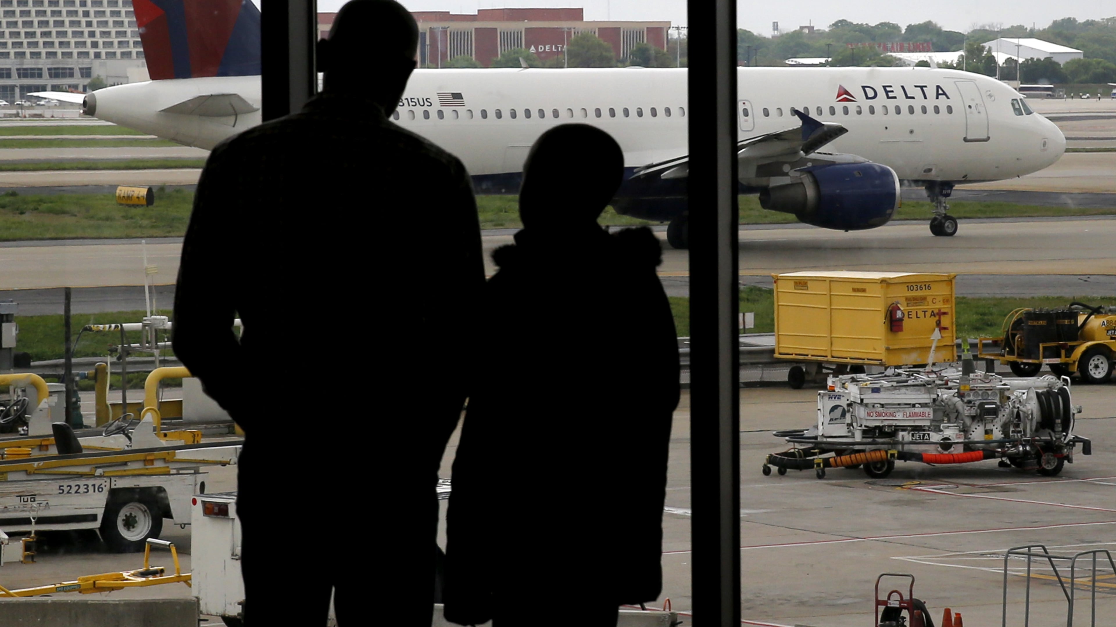 In this Tuesday, April 14, 2015 photo, travelers watch as a plane taxis at Hartsfield-Jackson Atlanta International Airport in Atlanta. After years of steadily-rising airfare, travelers this summer can expect a tiny bit of relief, a really tiny bit. The average roundtrip domestic ticket this summer now stands at $454, down $2.01 from last summer. Vacationers to Europe will fare better with tickets down 3 percent to $1,619, about $50 less. (AP Photo/Charles Rex Arbogast)