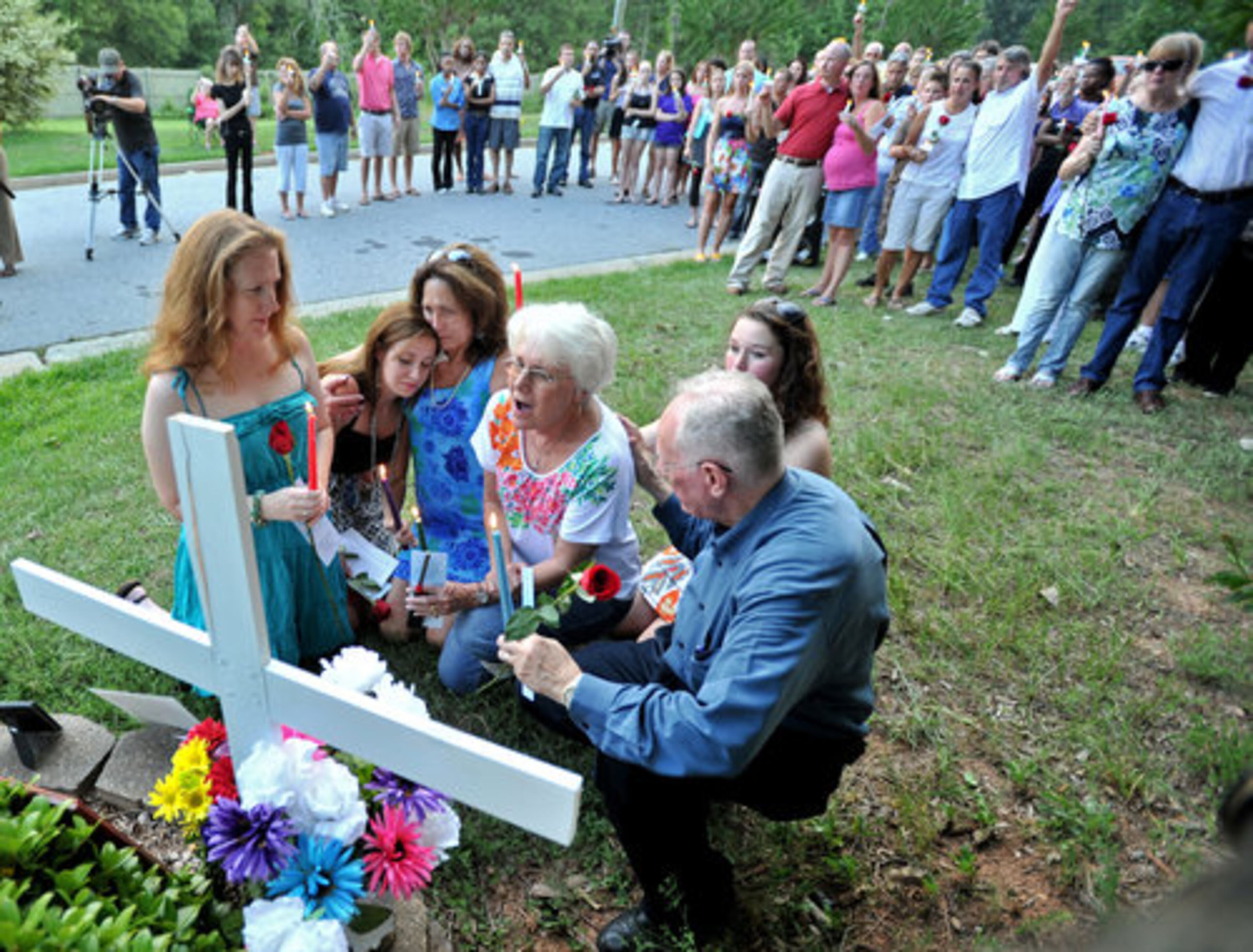 Members of Nique Leili's family (foreground from left) Amy Elk (sister), Alex Page (daughter), Kathy White (sister), Harriett Garrett (mother) and Doug Chatham (right, father) gather at a memorial during the candlelight vigil for Nique, whose body was discovered Saturday morning in the Oak Village subdivision in Lawrenceville.
