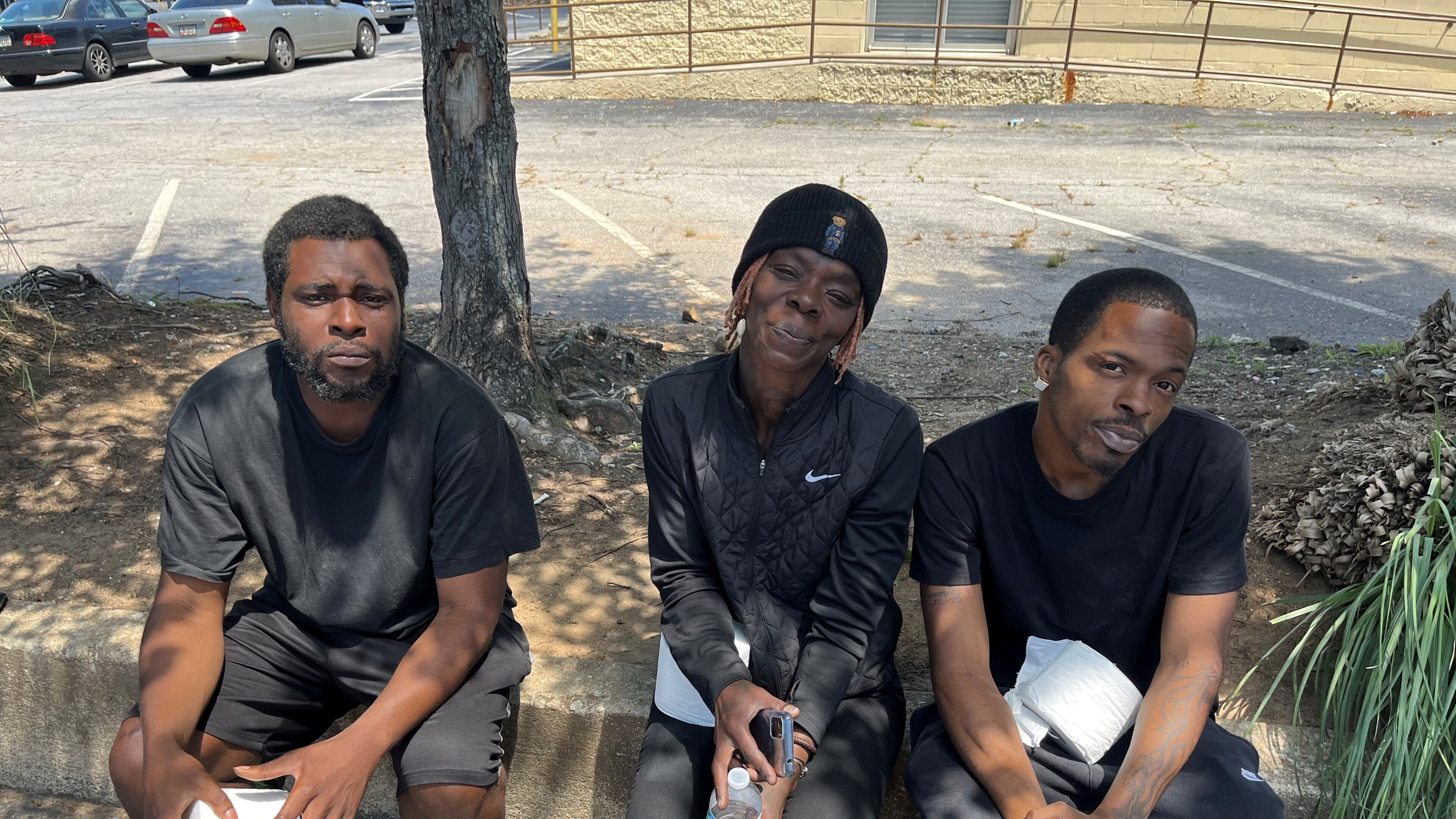 Three people who recently stayed at Haven Hotel in Stone Mountain, Georgia, hold rolls of toilet paper given to them by community volunteers. The hotel charges residents $1 per roll, they say. (Andy Miller for KFF Health News)