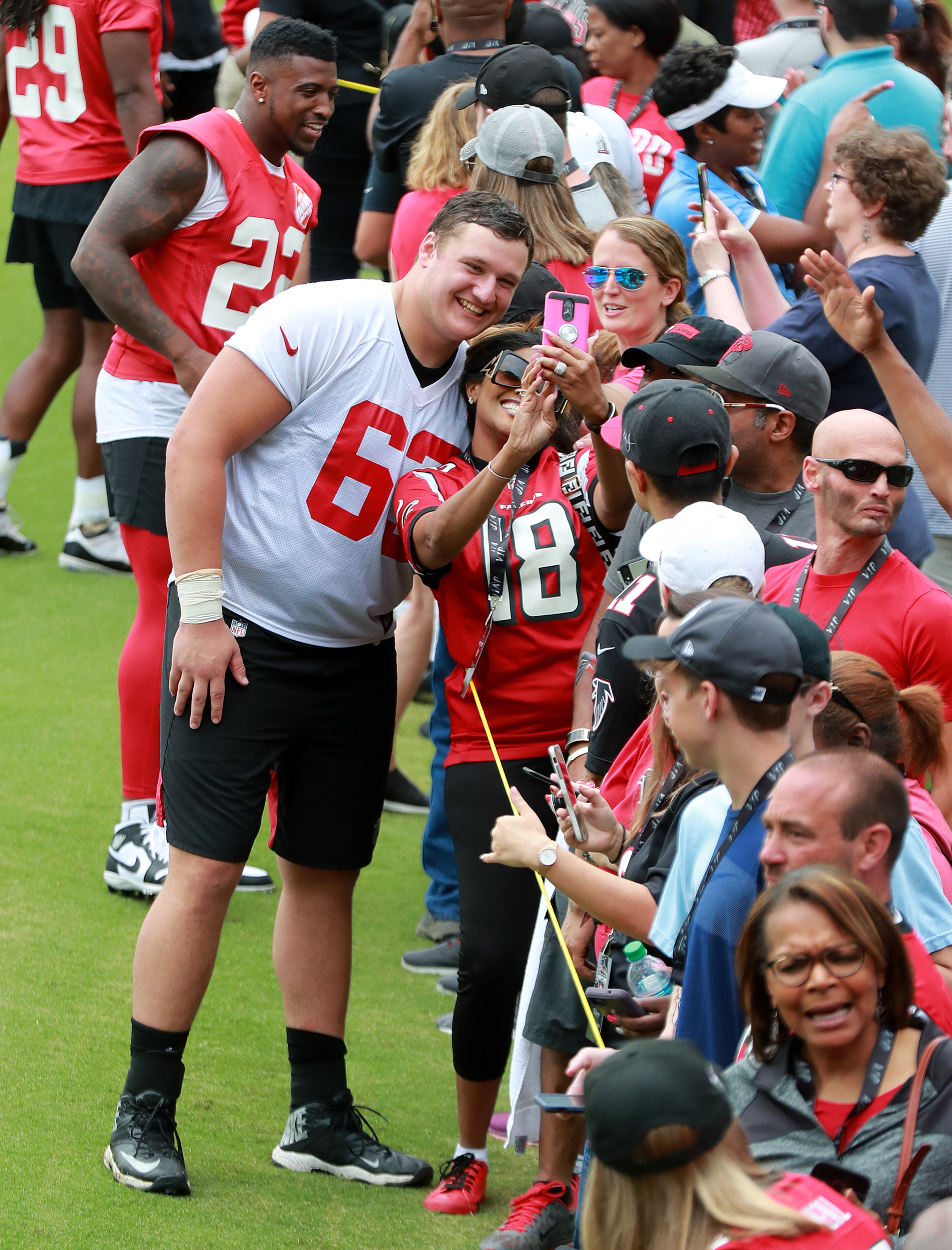 First-round pick Chris Lindstrom poses for a selfie while signing autographs fwith safety Keanu Neal in the background following Wednesday's practice. (Curtis Compton/ccompton@ajc.com)