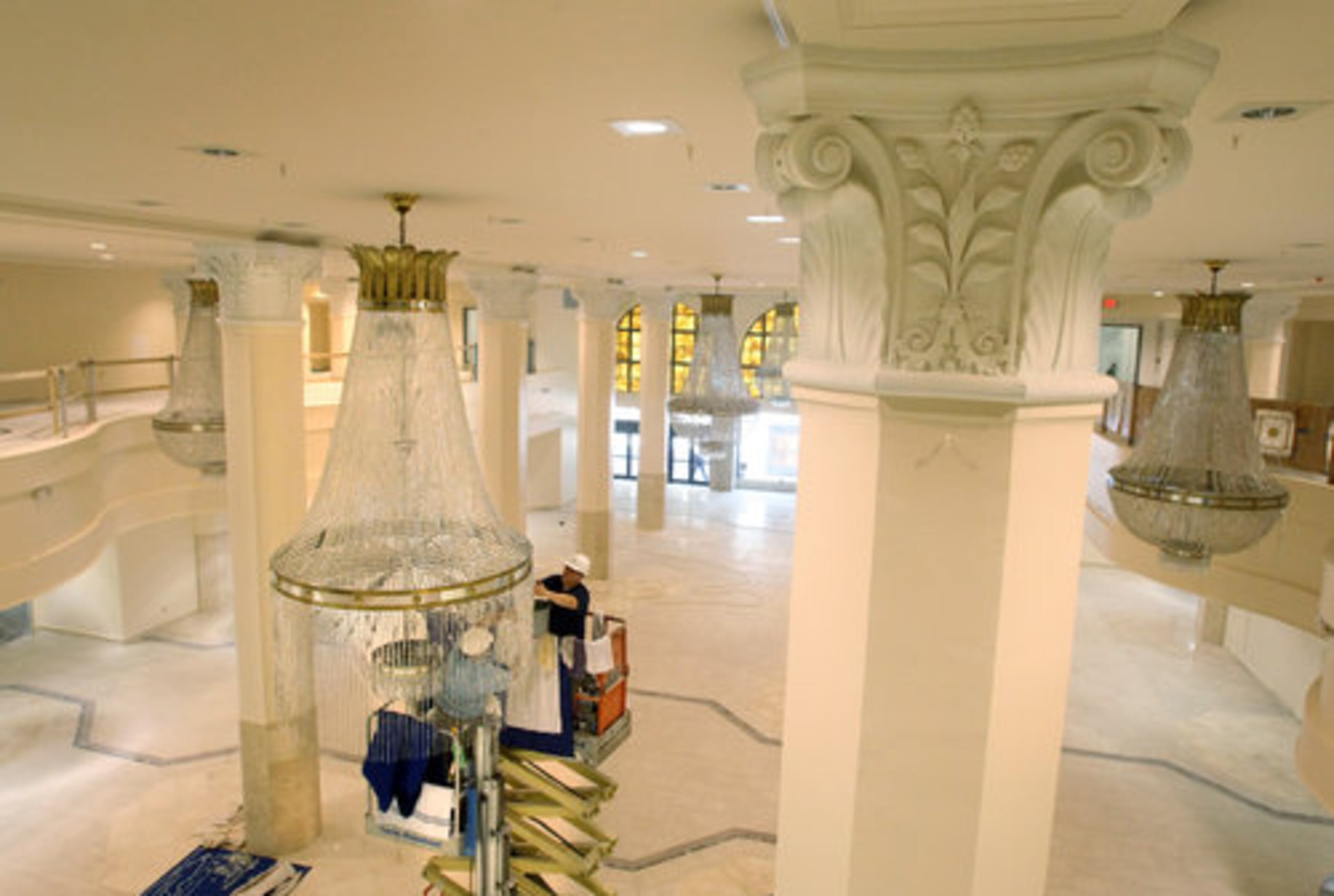 Workers use scissor lifts to reach the chandeliers. Part of the marble floor is original to the store, and part is matched with new marble from Greece.