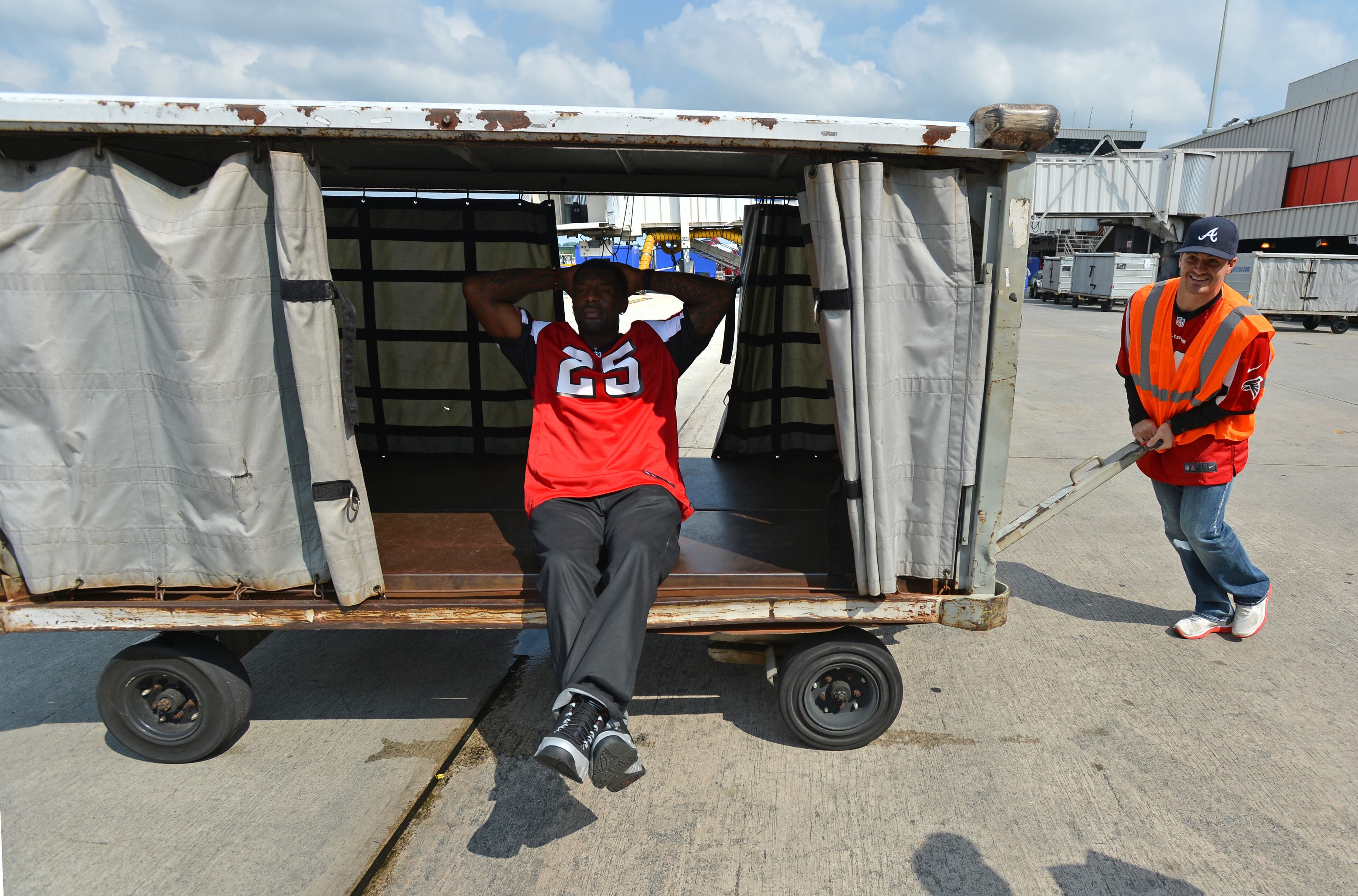 Atlanta Falcons safety William Moore gets a ride in a luggage cart from teammate Shann Schillinger while waiting to direct a plane away from the terminal.Five members of the Atlanta Falcons visited Southwest Airlines operations at Hartsfield-Jackson Atlanta International Airport with special guest Jordan Thomas. Thomas, 14, was diagnosed with cancer in 2012. As part of the Make-A-Wish Foundation, Thomas had the opportunity to hang out with members of the Falcons as they visited the Southwest ticket counter terminal, announced a flight departure and helped direct a plane away from the terminal. BRANT SANDERLIN /BSANDERLIN@AJC.COM