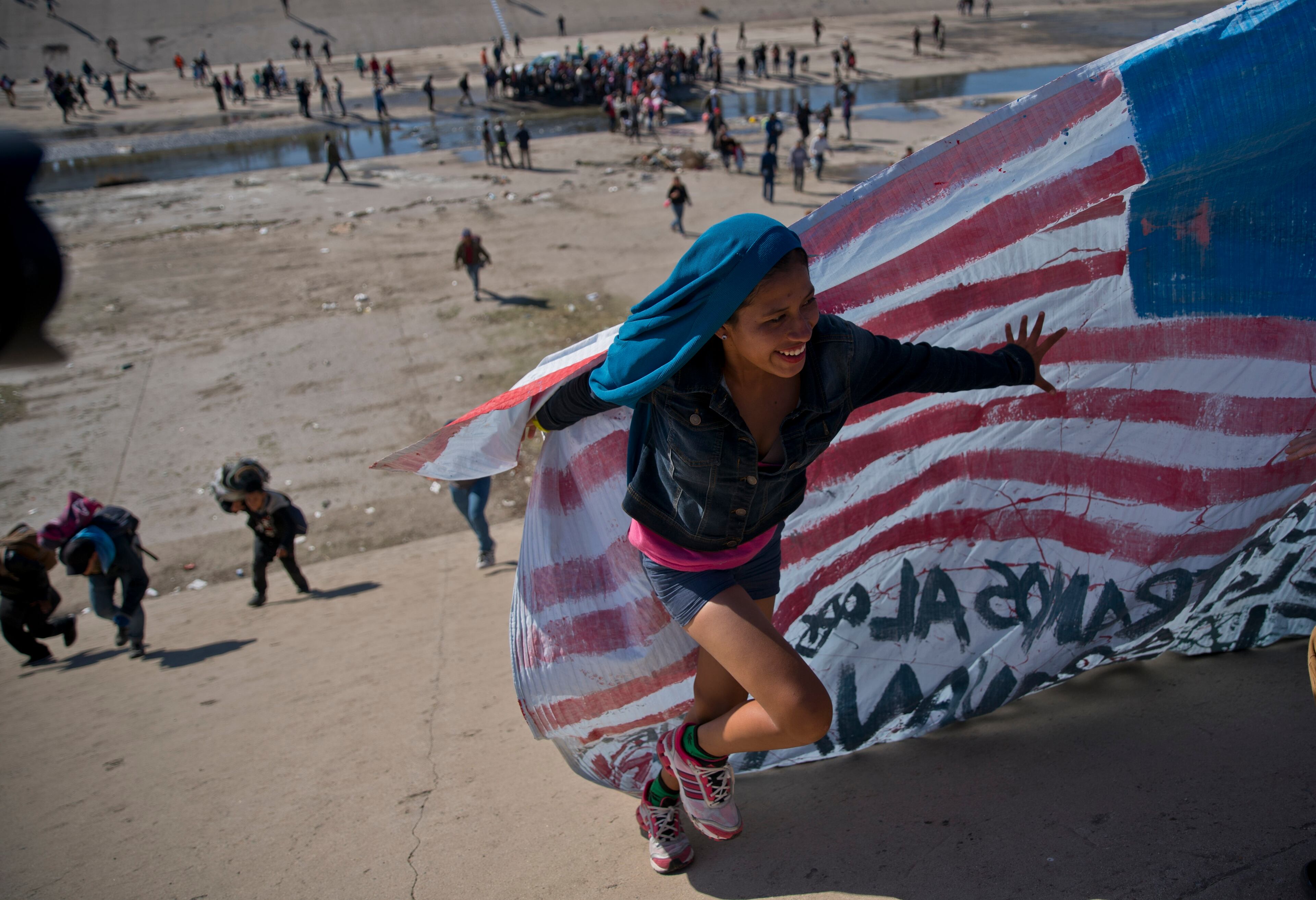 Migrants cross a riverbed at the Mexico-U.S. border after getting past a line of police at the Chaparral border crossing in Tijuana, Mexico, Sunday, Nov. 25, 2018, as they try to reach the U.S. The mayor of Tijuana has declared a humanitarian crisis in his border city and says that he has asked the United Nations for aid to deal with the approximately 5,000 Central American migrants who have arrived in the city. (AP Photo/Ramon Espinosa)