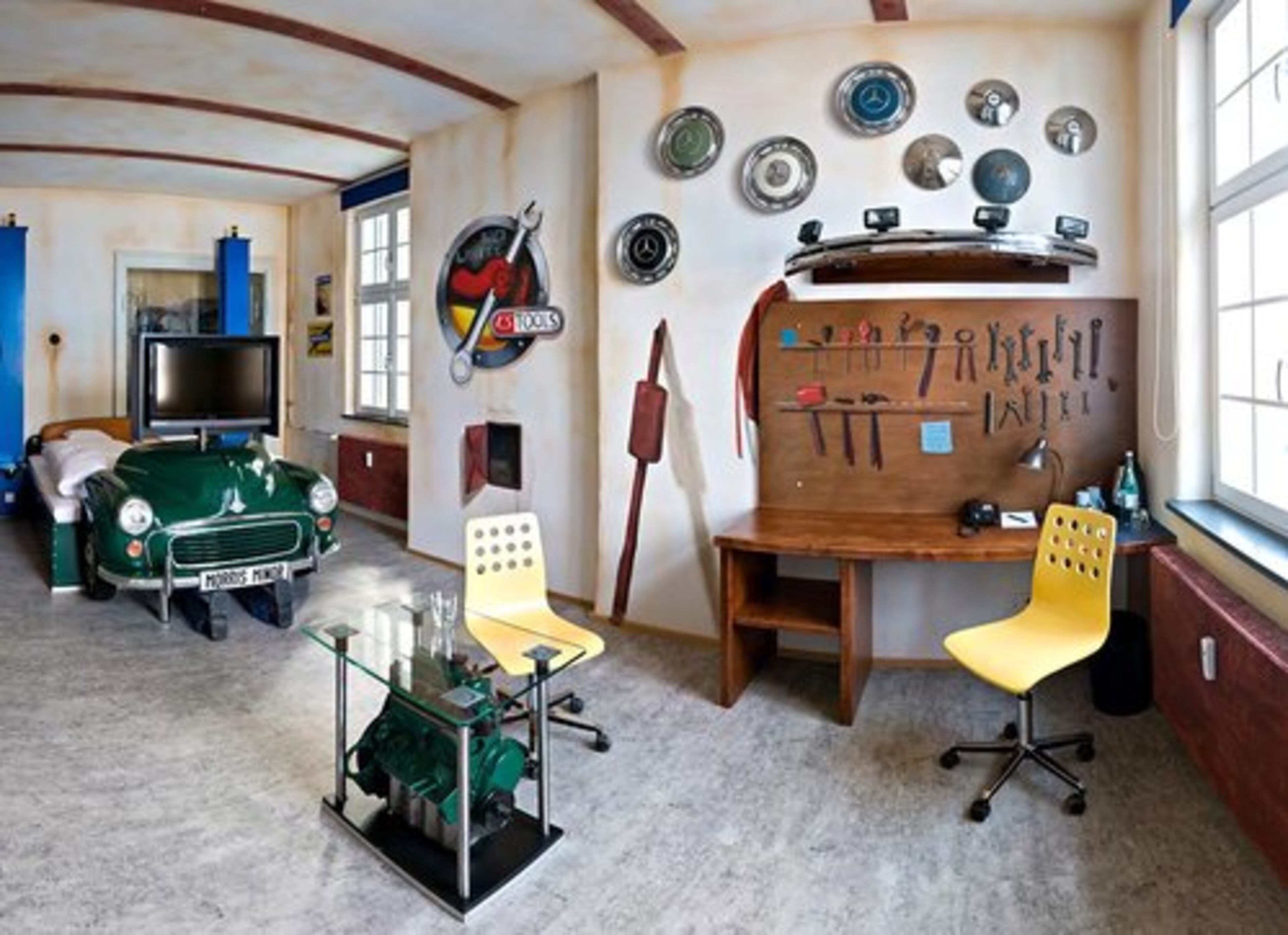 For those that spend their weekends under the hood of their car, the mechanic's workshop room will make for an interesting place to recharge your engine. The workshop space, complete with an array of tools, also serves as a desk. Check out the end of the bed, with the feet of a mechanic hard at work below it!