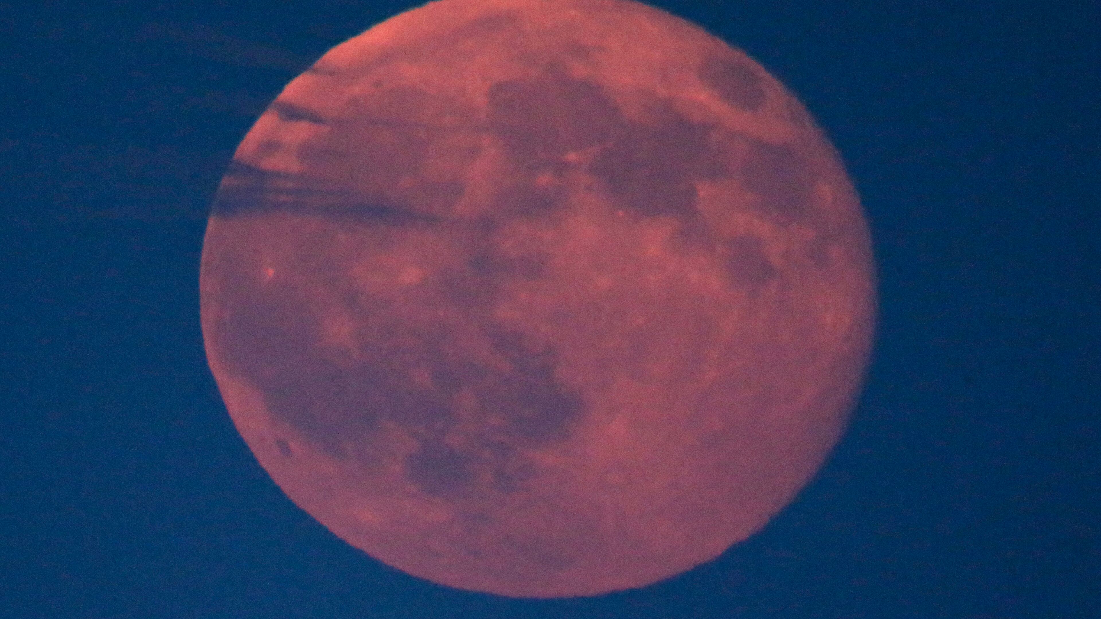 A blue moon is is diffused by clouds as it rises Friday, July 31, 2015, in Kansas City, Mo. (AP Photo/Charlie Riedel)