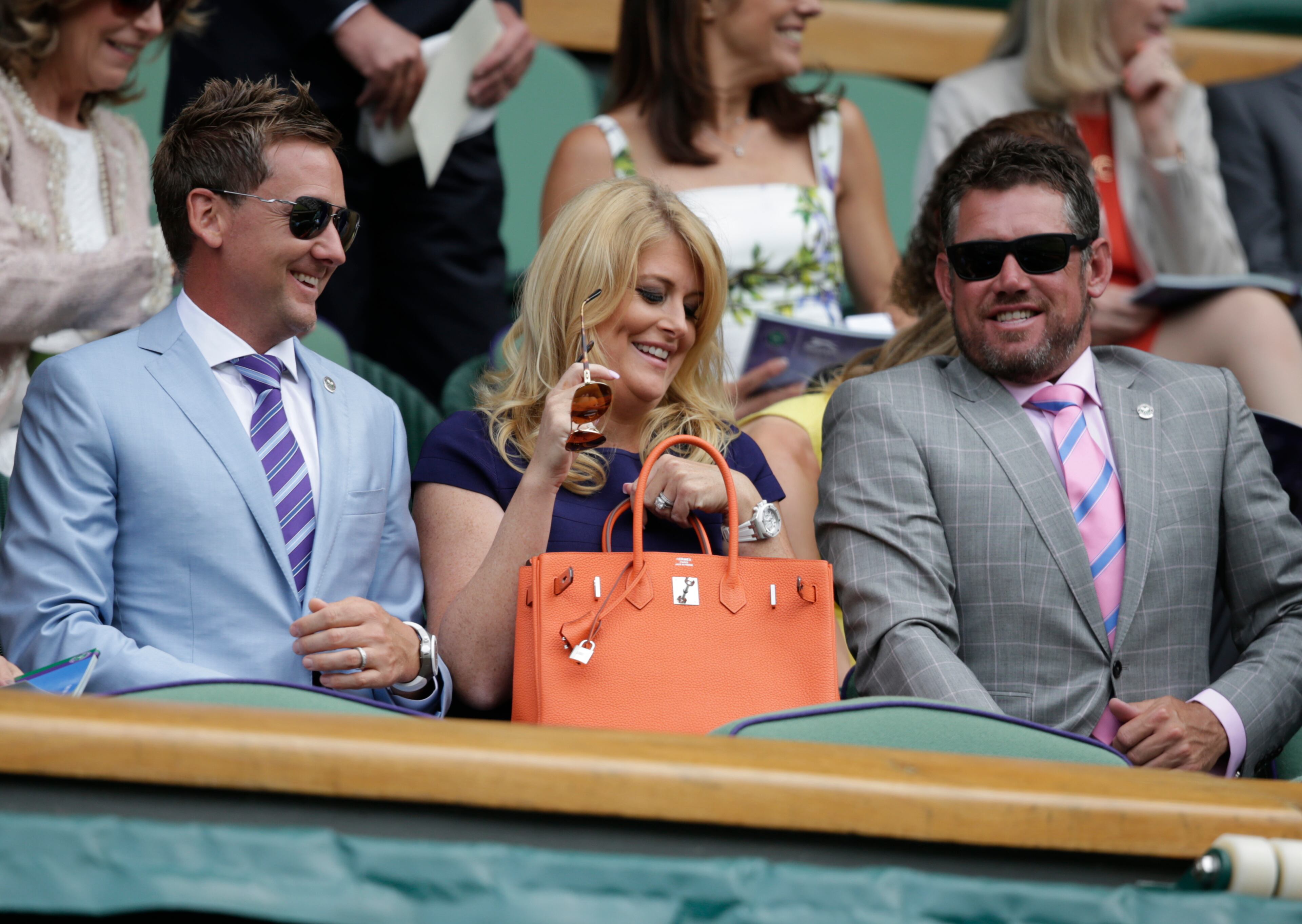 Golfer Ian Poulter, his wife Katie and fellow golfer Lee Westwood, take their seats prior to the start of the singles match between Serena Williams of the United States and Venus Williams of the United States, at the All England Lawn Tennis Championships in Wimbledon, London, Monday July 6, 2015. (AP Photo/Alastair Grant)