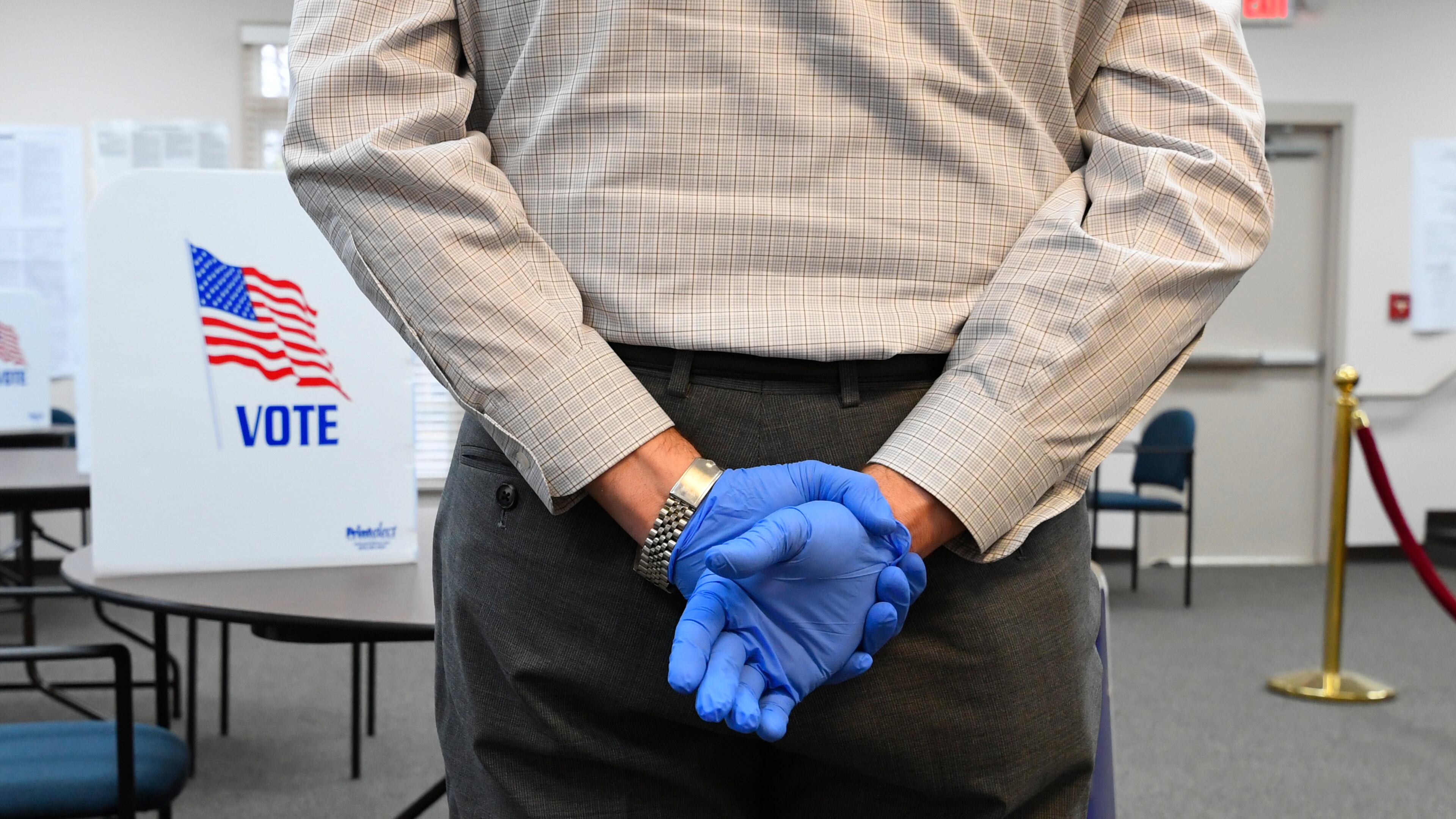 A poll worker wearing protective gloves waits to assist voters during special election voting at city hall to fill an empty city council seat on Tuesday, March 24, 2020, in Dacula. The voting happens to on a day that was supposed to be the test run for the state's new election system before coronavirus COVID-19 caused it to be called off.