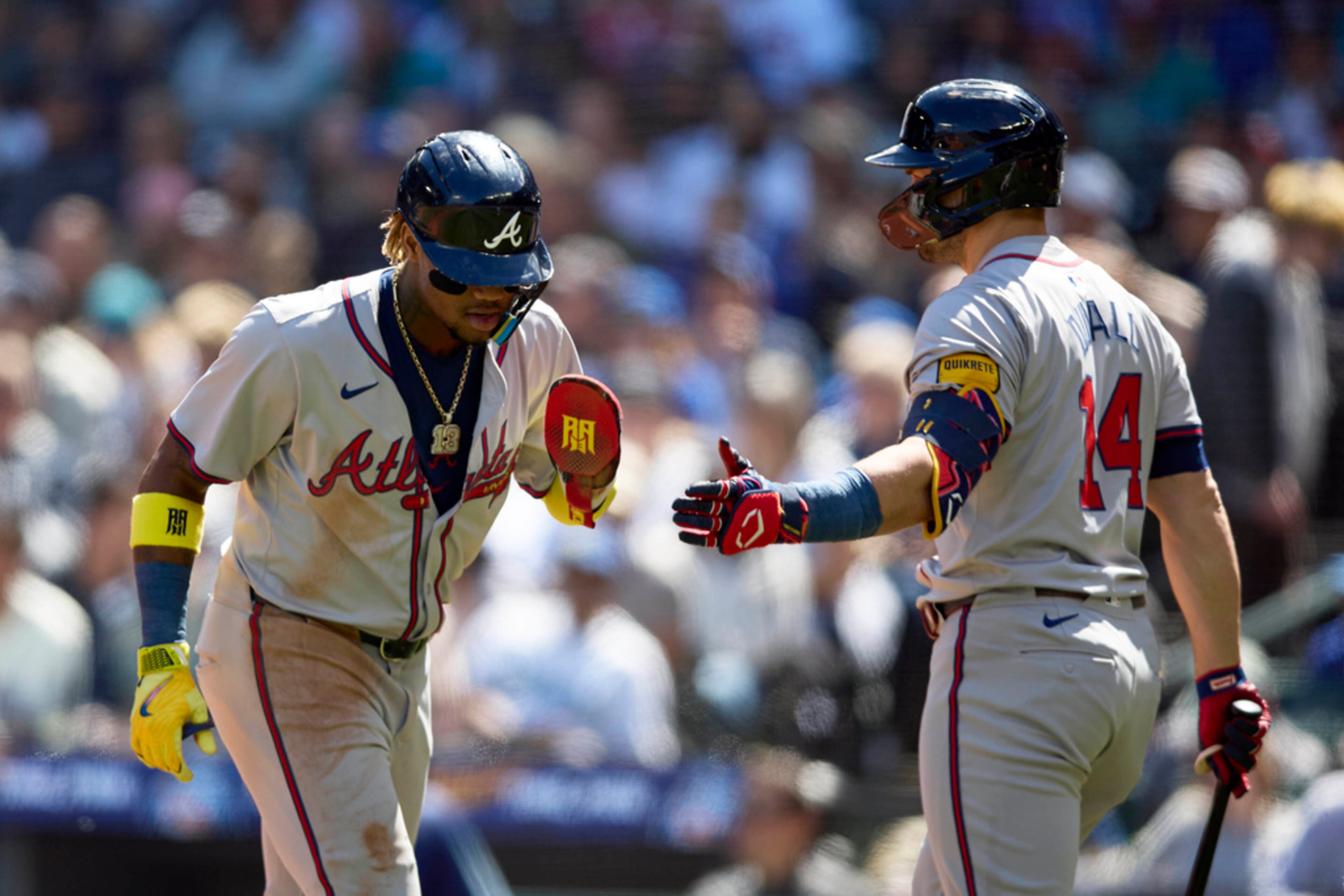 Atlanta Braves' Ozzie Albies, left, is congratulated by Adam Duvall after scoring on a bases loaded walk against the Seattle Mariners during the third inning of a baseball game, Wednesday, May 1, 2024, in Seattle. (AP Photo/John Froschauer)