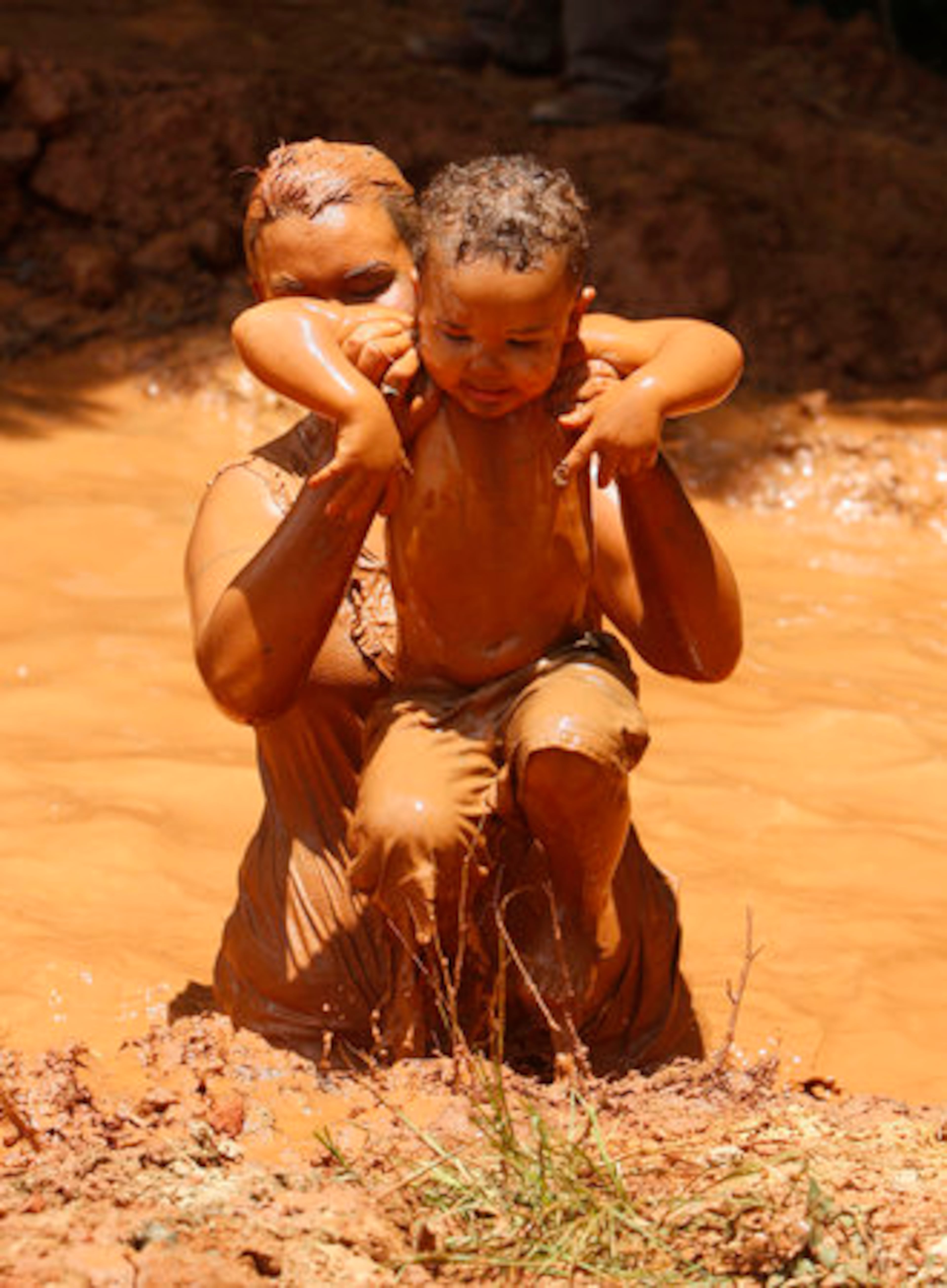 C.D. Lewis, 2, is helped out of the mud pit by his mother, Beth Lewis, of Barnesville, GA. during the 13th Annual Redneck Games in East Dublin on Saturday.
