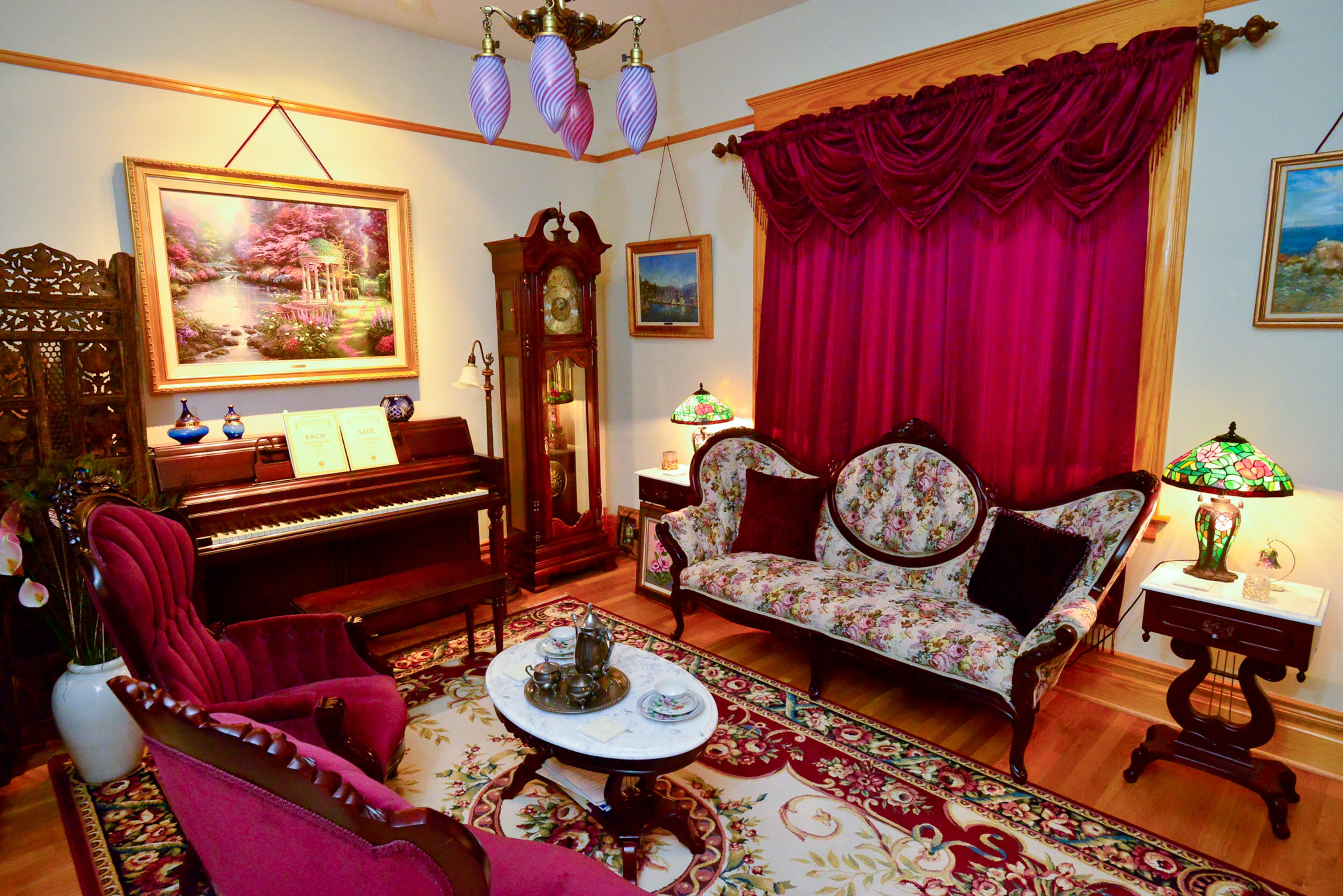 A Thomas Kinkade painting, which the Dufanos started collecting eight years ago, hangs over the piano in the library of their Grant Park home. The floral sofa, plush chairs and marble-top coffee table are "faux antiques," the couple said. Books are hidden behind the screen next to the piano, and the couple plans to eventually add bookshelves to the room.