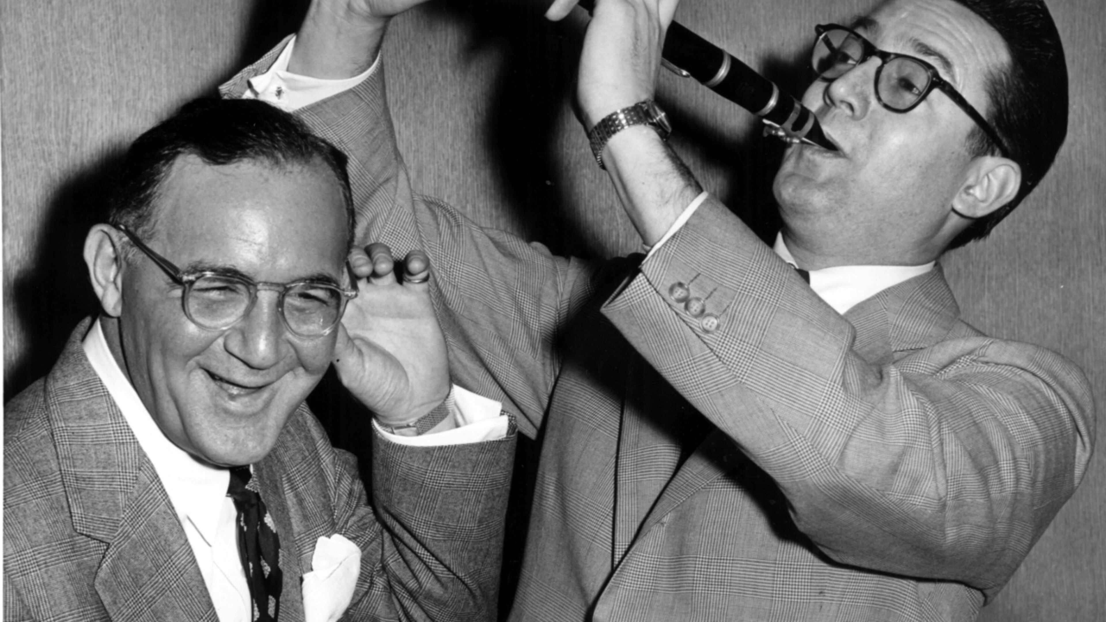 April 20, 1955 - New York: Benny Goodman, the ‘King of Swing’ himself, can hardly believe his ears as comedian Steve Allen makes with a few hot licks on the ‘licorice stick.’ Goodman, who is usually on the business end of the clarinet, is soon to be honored by a Hollywood film biography. Allen has been selected to play goodman in the forthcoming ‘Benny Goodman Story’ and the jazz great seem to like the idea. (Credit: United Press Photo) 4-20-55