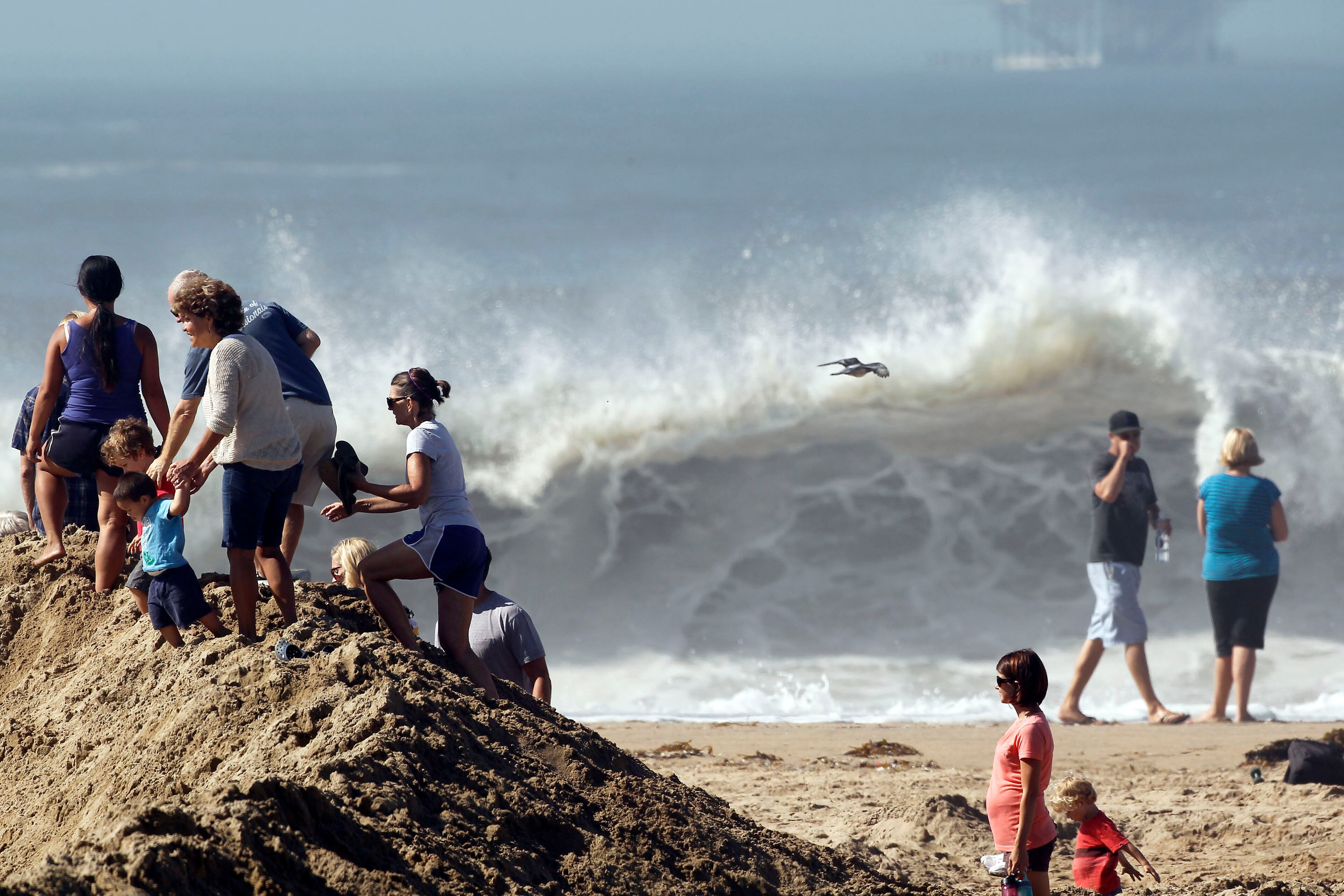 Onlookers standing on a sand berm watch as big waves come into shore from Hurricane Marie in Seal Beach, Calif. on Wednesday, Aug. 27, 2014. The National Weather Service said beaches stretching 100 miles up the Southern California coast would see large waves and rip currents. Swimmers and surfers were urged to be aware of the dangerous conditions. (AP Photo/ Nick Ut )