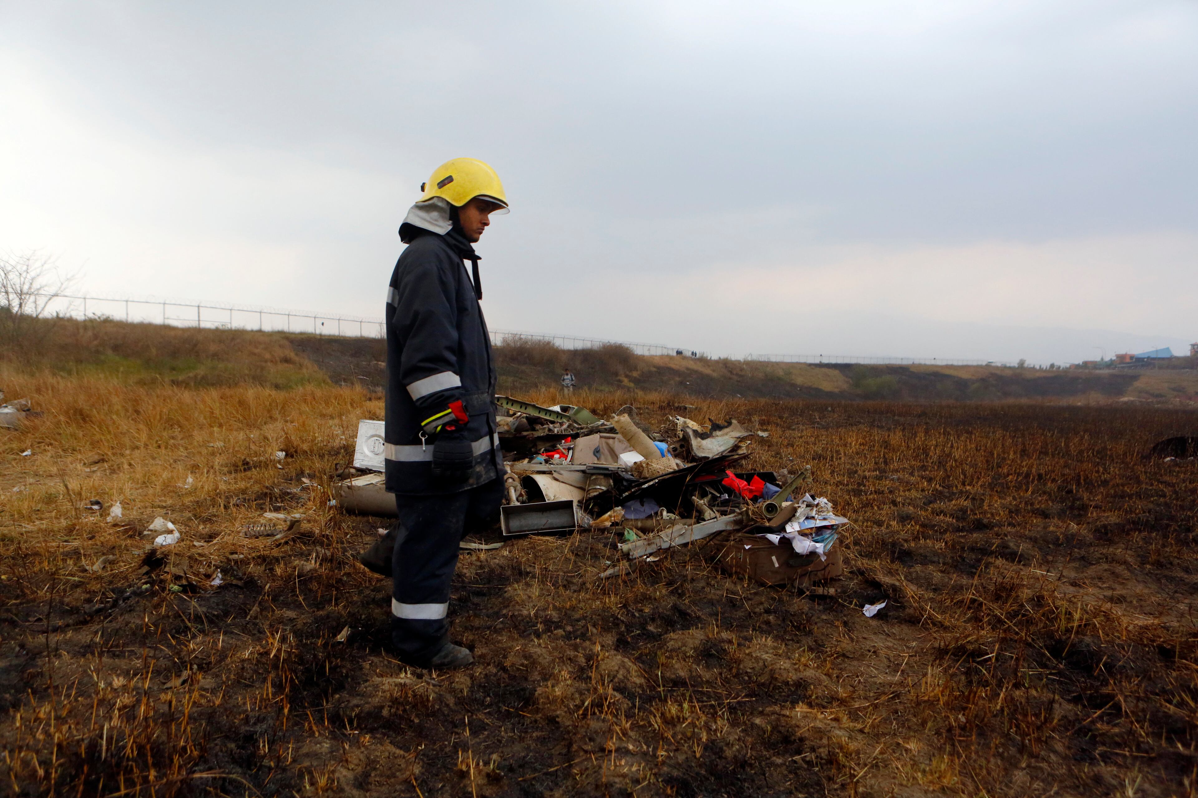 A Nepalese rescue worker stands near the debris after a passenger plane from Bangladesh crashed at the airport in Kathmandu, Nepal, Monday, March 12, 2018. The passenger plane carrying 71 people from Bangladesh crashed and burst into flames as it landed Monday in Kathmandu, Nepal's capital, killing dozens of people, officials said. (AP Photo/Niranjan Shreshta)