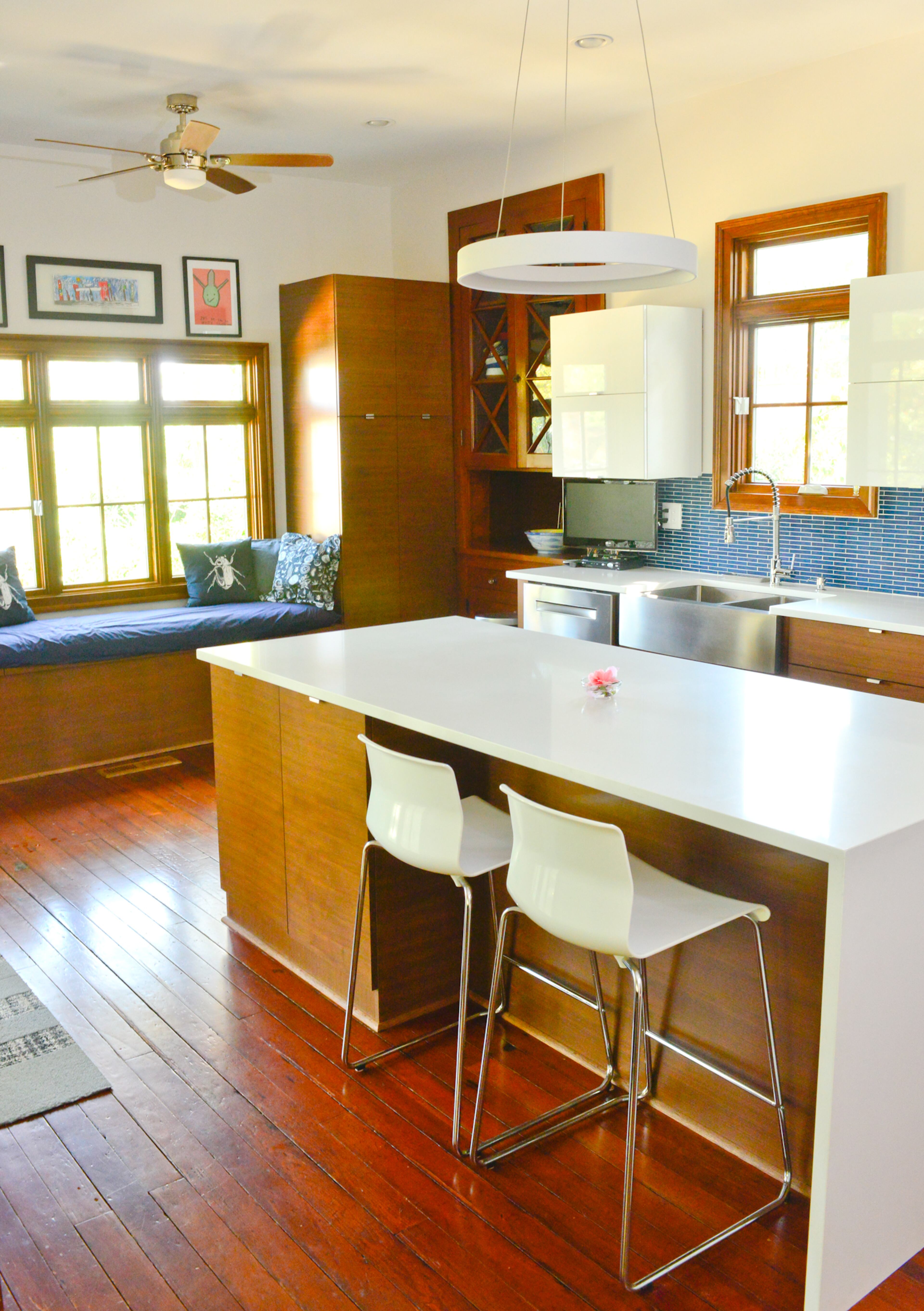Bar stools from IKEA and a ring light fixture from Progressive Lighting bring sleek, yet simple, style to the renovated Inman Park kitchen. Trim Line Construction found the horizontal grain walnut they wanted for the custom bottom kitchen cabinets and to rebuild the window seat. The upper white cabinets are from IKEA.