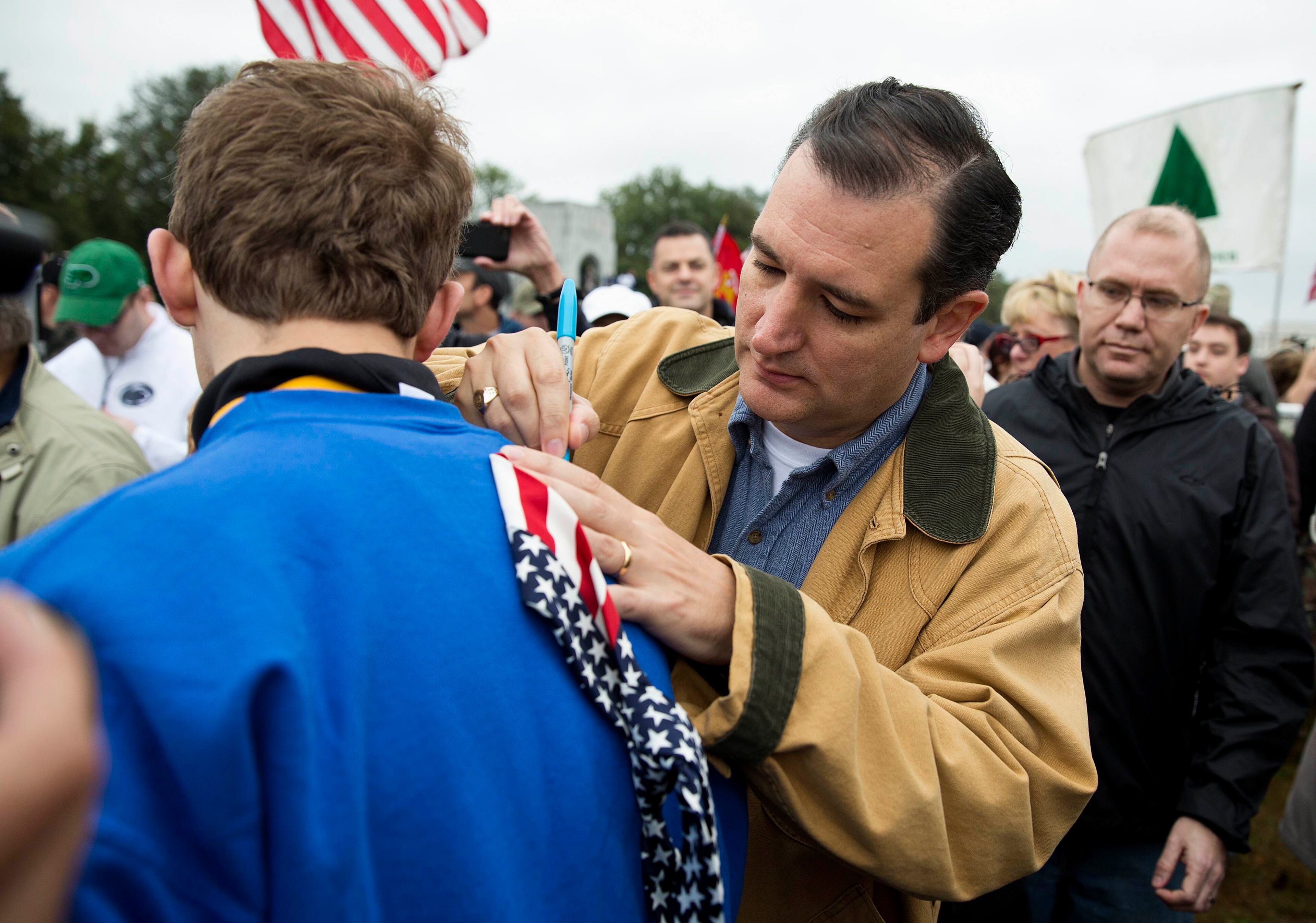Senator Ted Cruz (R-TX) signs a tie for a supporter at the "Million Vet March on the Memorials" at the U.S. National World War II Memorial in Washington October 13, 2013. The group was organized in protest of the Obama administration's decision to close the memorial and bar entry to World War Two vets who had traveled to visit it during the partial government shut down. REUTERS/Joshua Roberts (UNITED STATES - Tags: POLITICS BUSINESS EMPLOYMENT MILITARY CIVIL UNREST)
