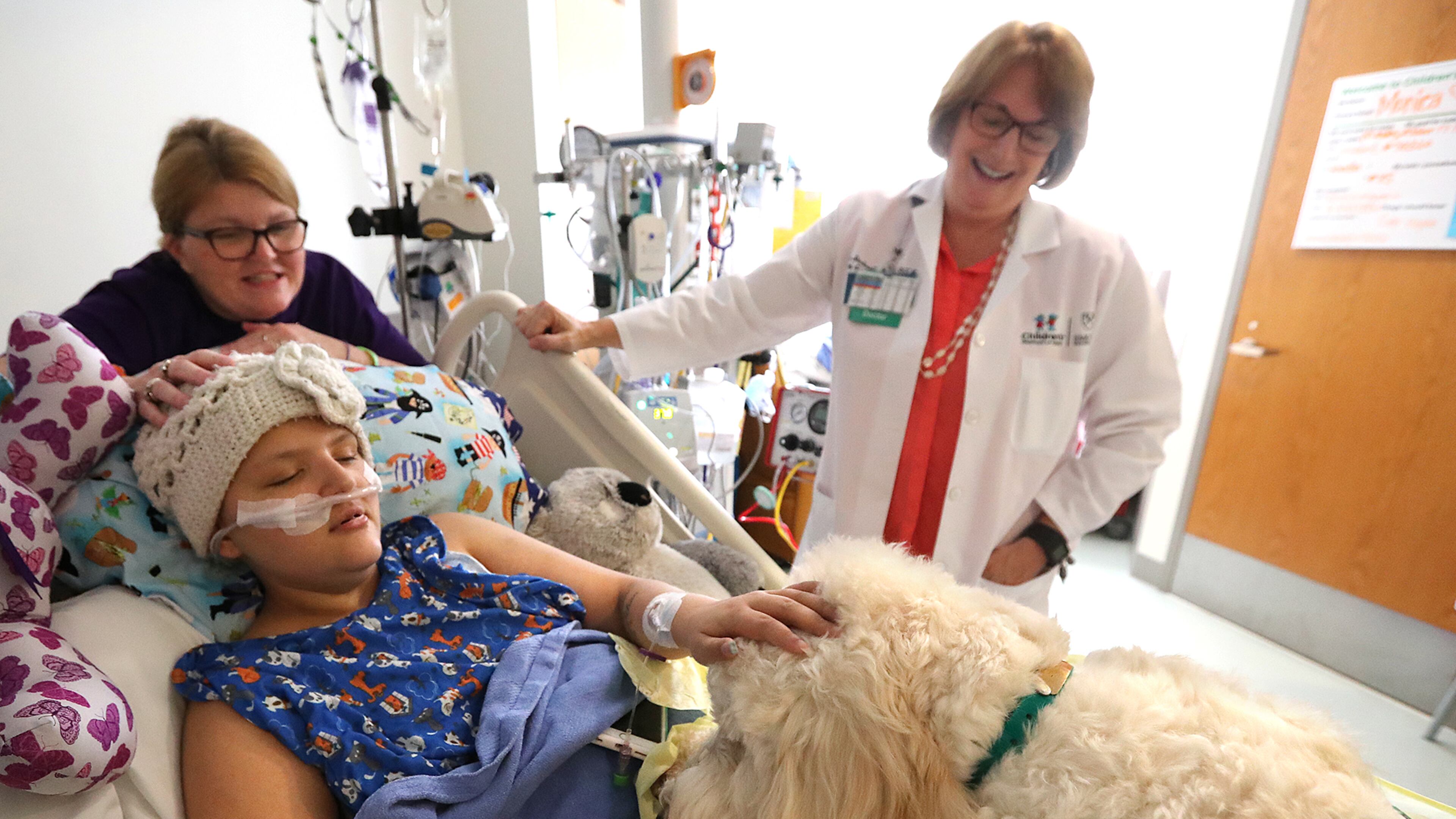 Doctor Jana Stockwell and Tidings make a stop to help cheer up Jeannie Sandoval and her daughter Monica, who has leukemia, during their rounds in the pediatric intensive care unit at Children’s Healthcare of Atlanta at Egleston. Tidings gets a pat on the head while licking Monica’s hand. Curtis Compton /ccompton@ajc.com