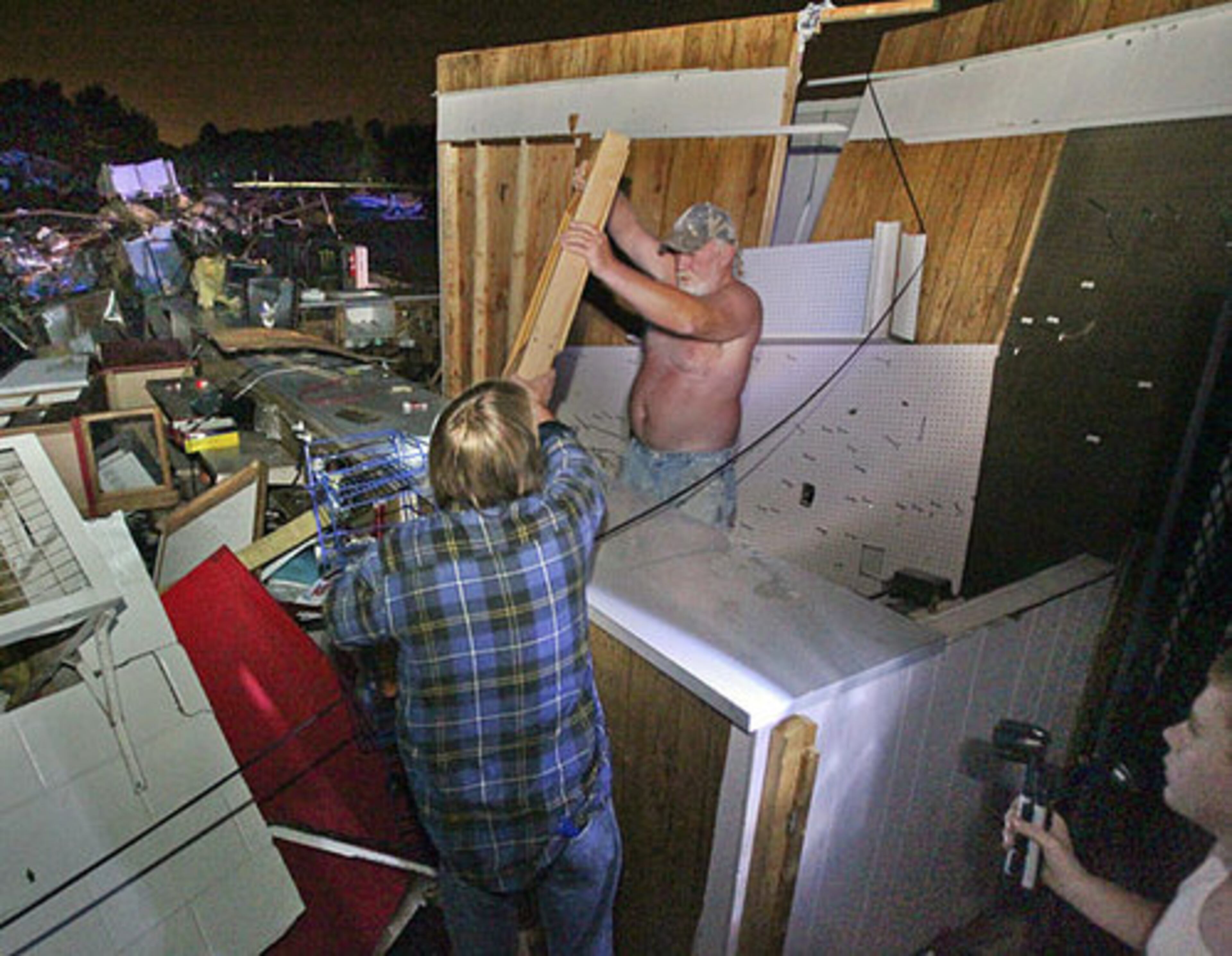 Owner of the Shell Station, Roy Brown (left) and Tim Bennett remove important items from his convenience store office Thursday, Apr. 28, 2011 as 15-year old, Jonathan Bennett looks on after the store was destroyed in Spalding County, Ga.