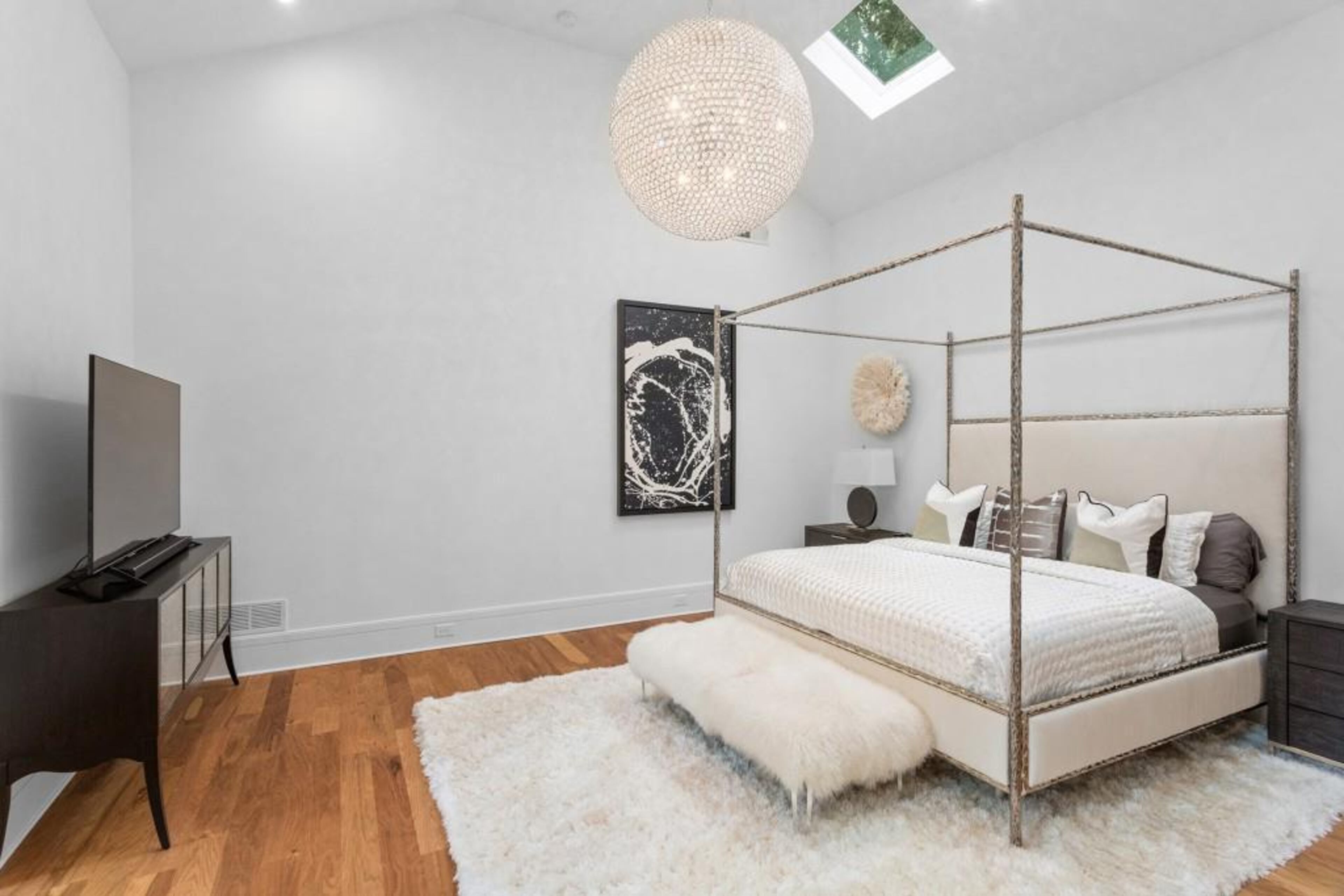 Oversized primary suite on main features 15-plus foot ceilings and spa bath featuring double vanity, soaking tub, frameless shower, and custom closet.