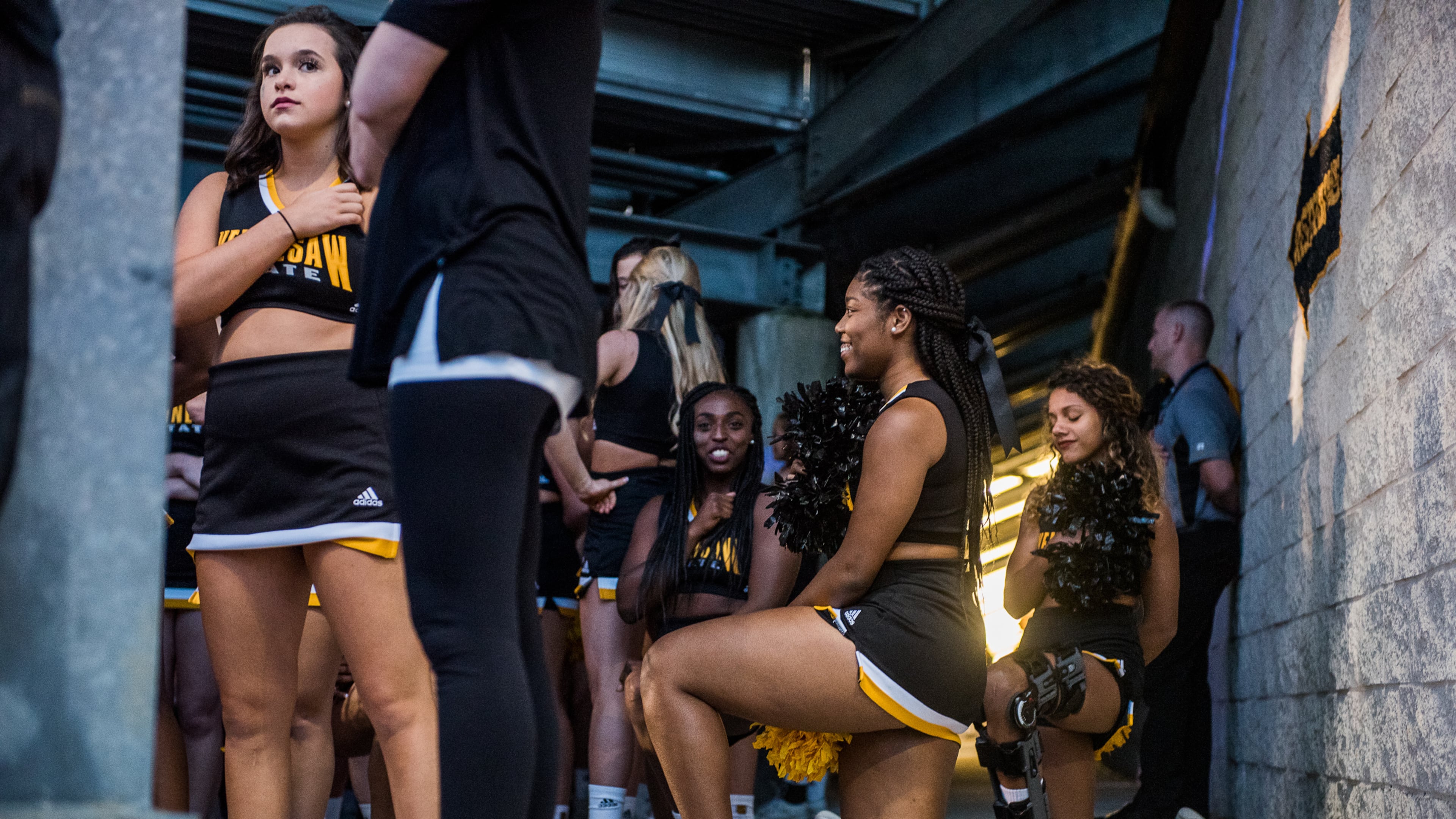 Three cheerleaders are seen kneeling in the tunnel by the field during the national anthem before Saturday's matchup between Kennesaw State and Gardner-Webb, Saturday, Oct. 21, 2017. (Special by Cory Hancock) Four cheerleaders kneeled during the anthem to continue the protests at KSU football games.