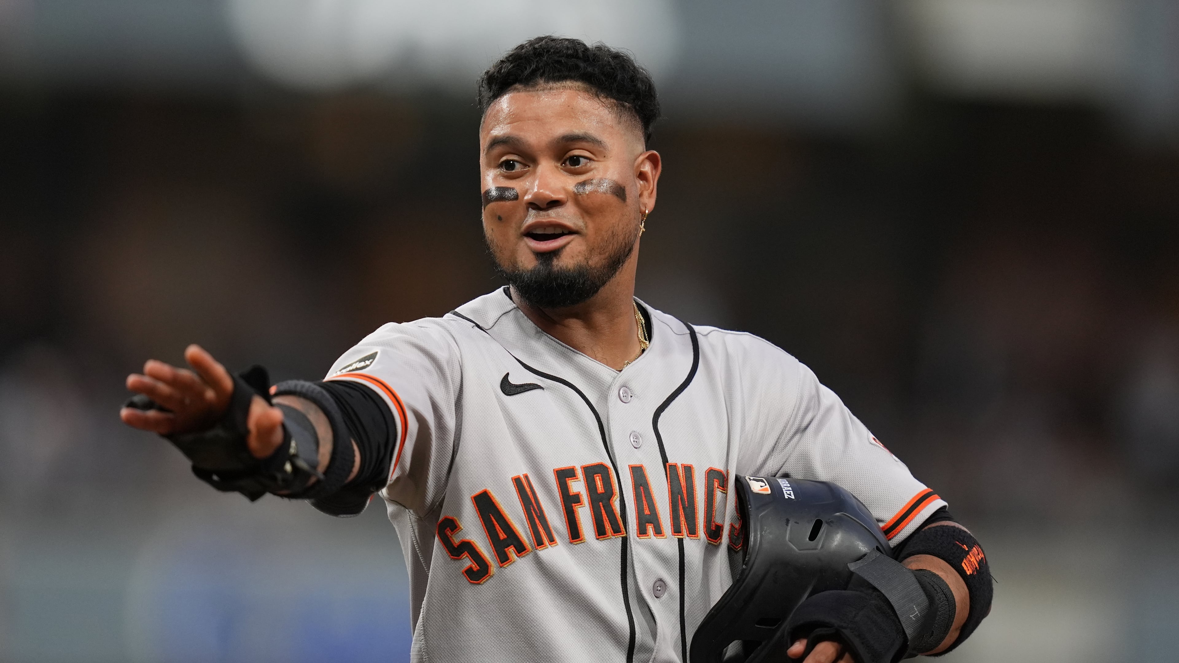 San Francisco Giants' Luis Arraez jokes with players in the San Diego Padres dugout as he stands on first base after getting hit by a pitch during the fourth inning of a baseball game Thursday, July 30, 2026, in San Diego. (AP Photo/Gregory Bull)