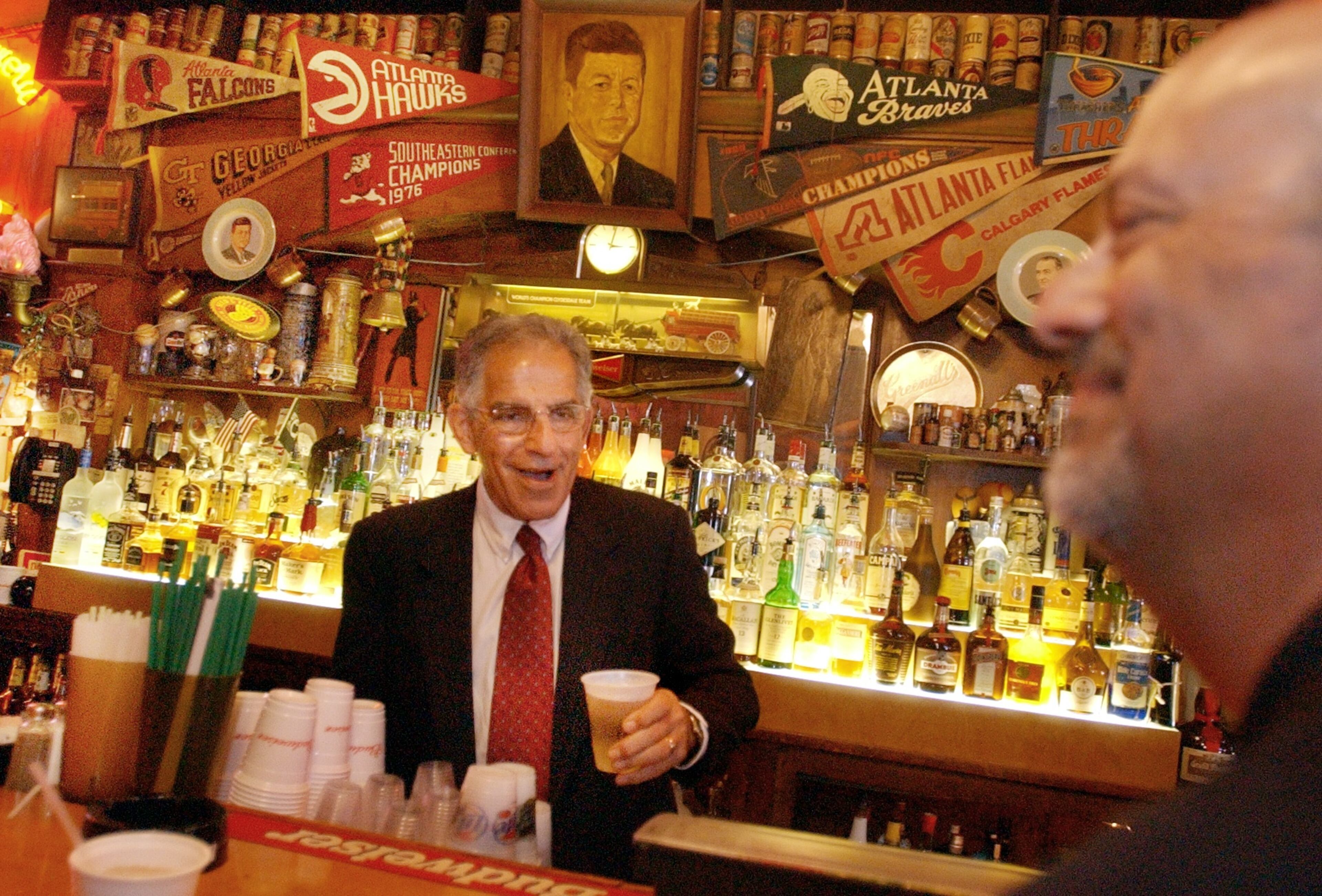 Robert Maloof, brother of Manuel Maloof, behind the bar at Manuel's, telling stories about his brother during a wake at Manuel's, for former DeKalb CEO, Manuel Maloof. Also pictured far right is Harry Kuniansky. (JOEY IVANSCO/AJC staff).